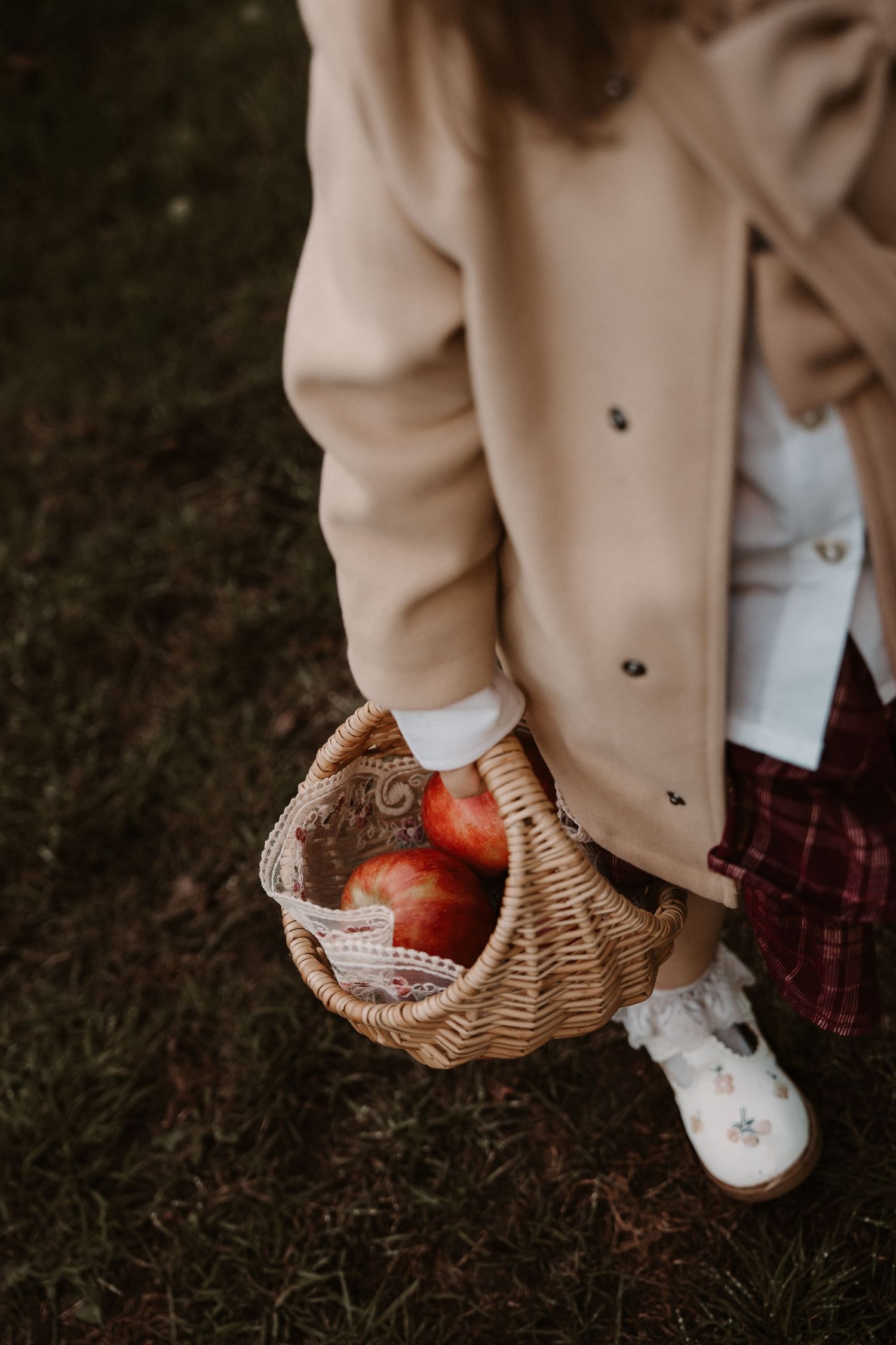 Basket filled with apples held by a child in warm autumn tones during a cozy outdoor session in Elford