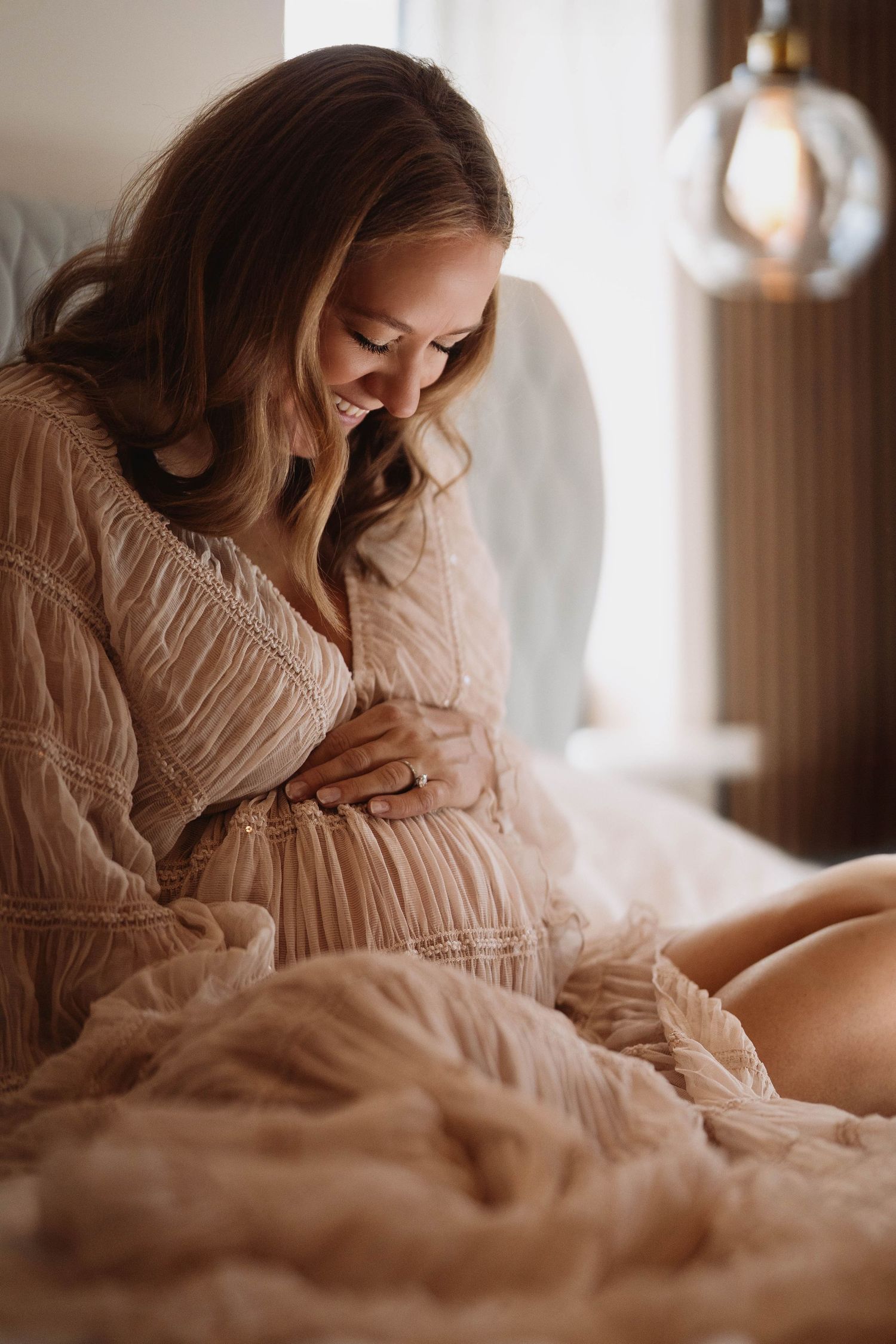 Pregnant parent resting by the window during an intimate in-home documentary maternity photography session.