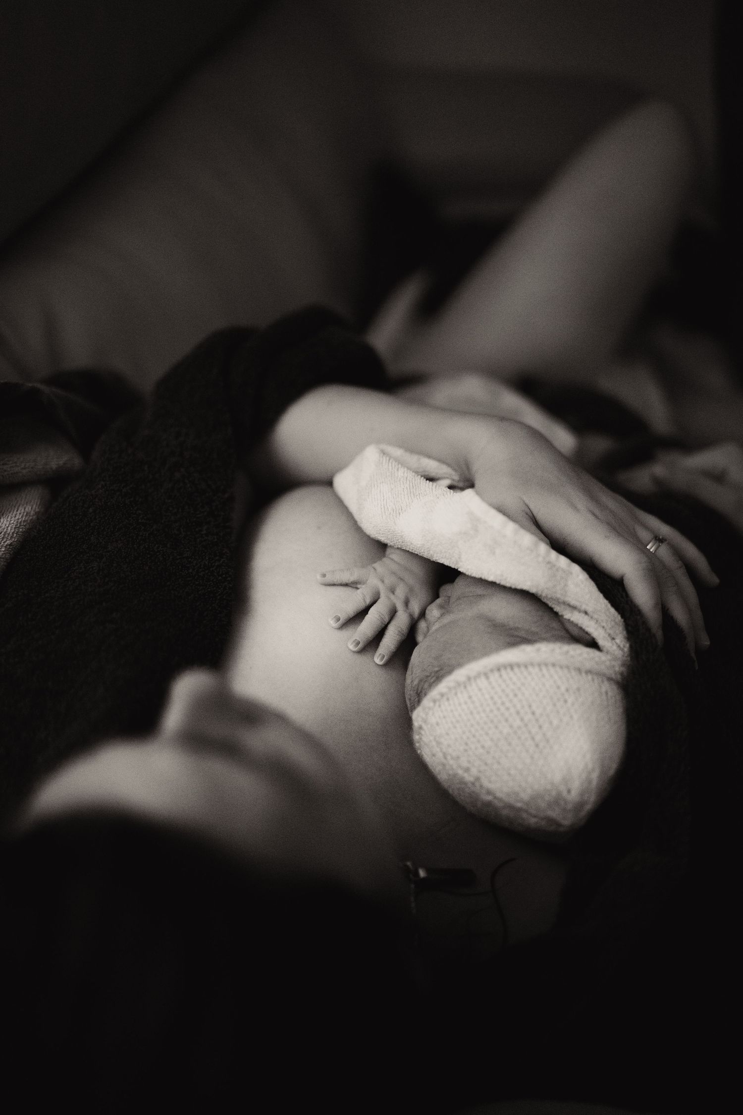 Parent resting together after birth, cradling their newborn during a raw documentary home birth moment.