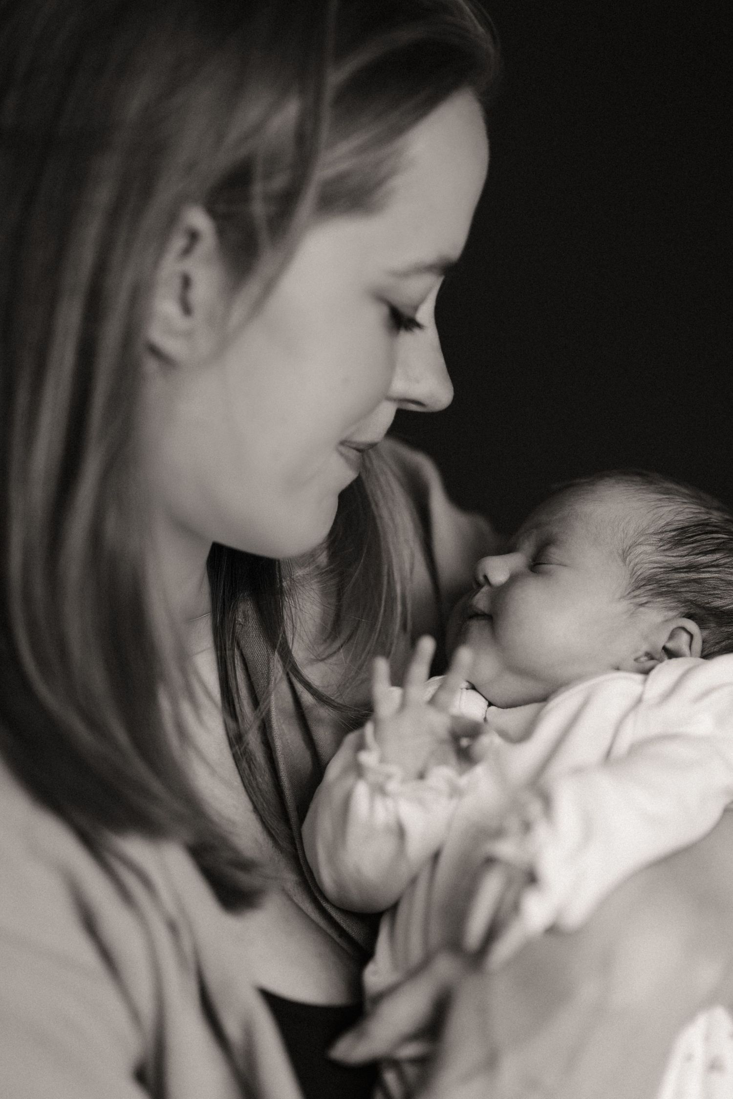Mother gazing at her baby during a quiet storytelling newborn photoshoot in black and white in Swadlincote