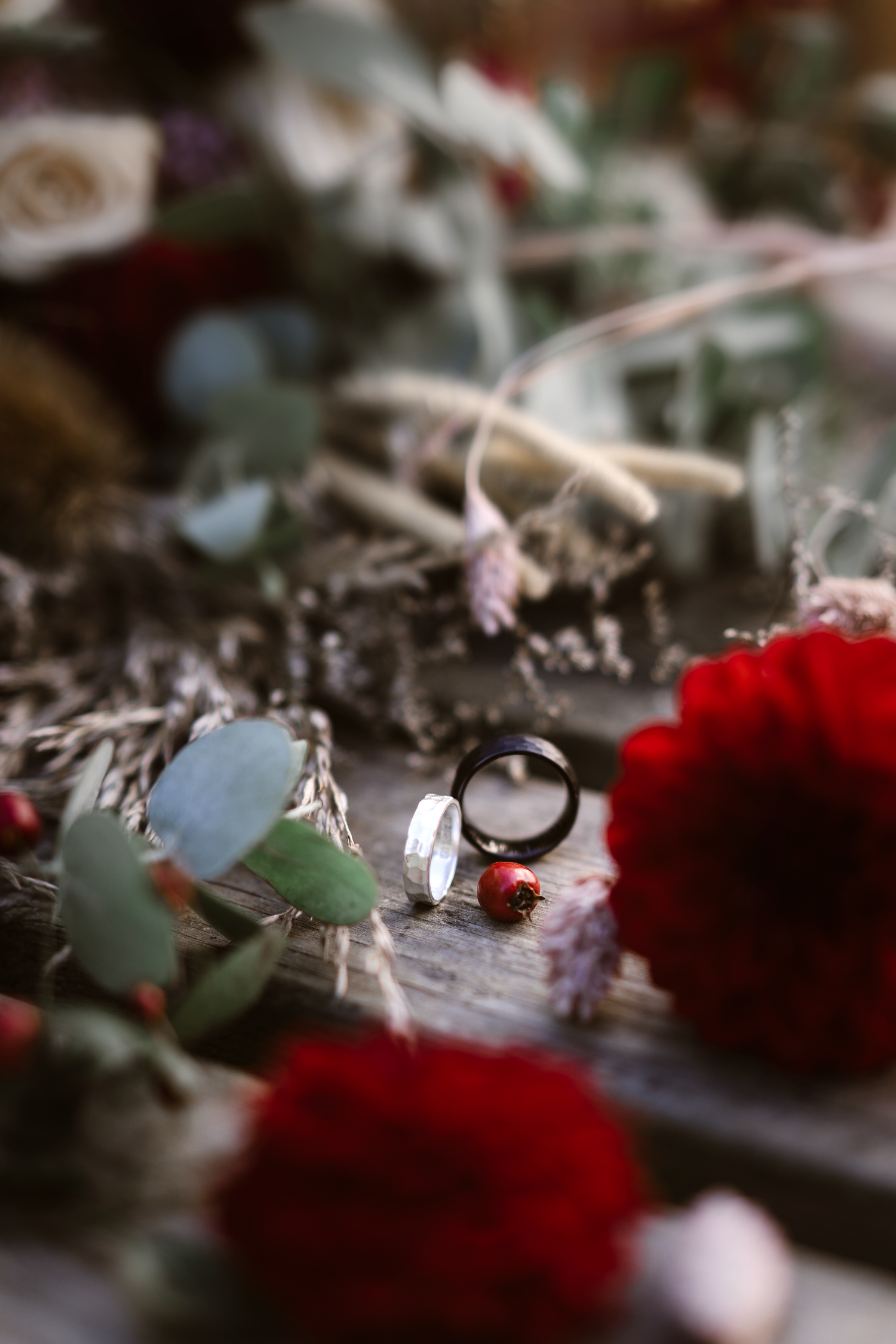 Wedding rings placed among flowers and foliage during a creative wedding detail shot.