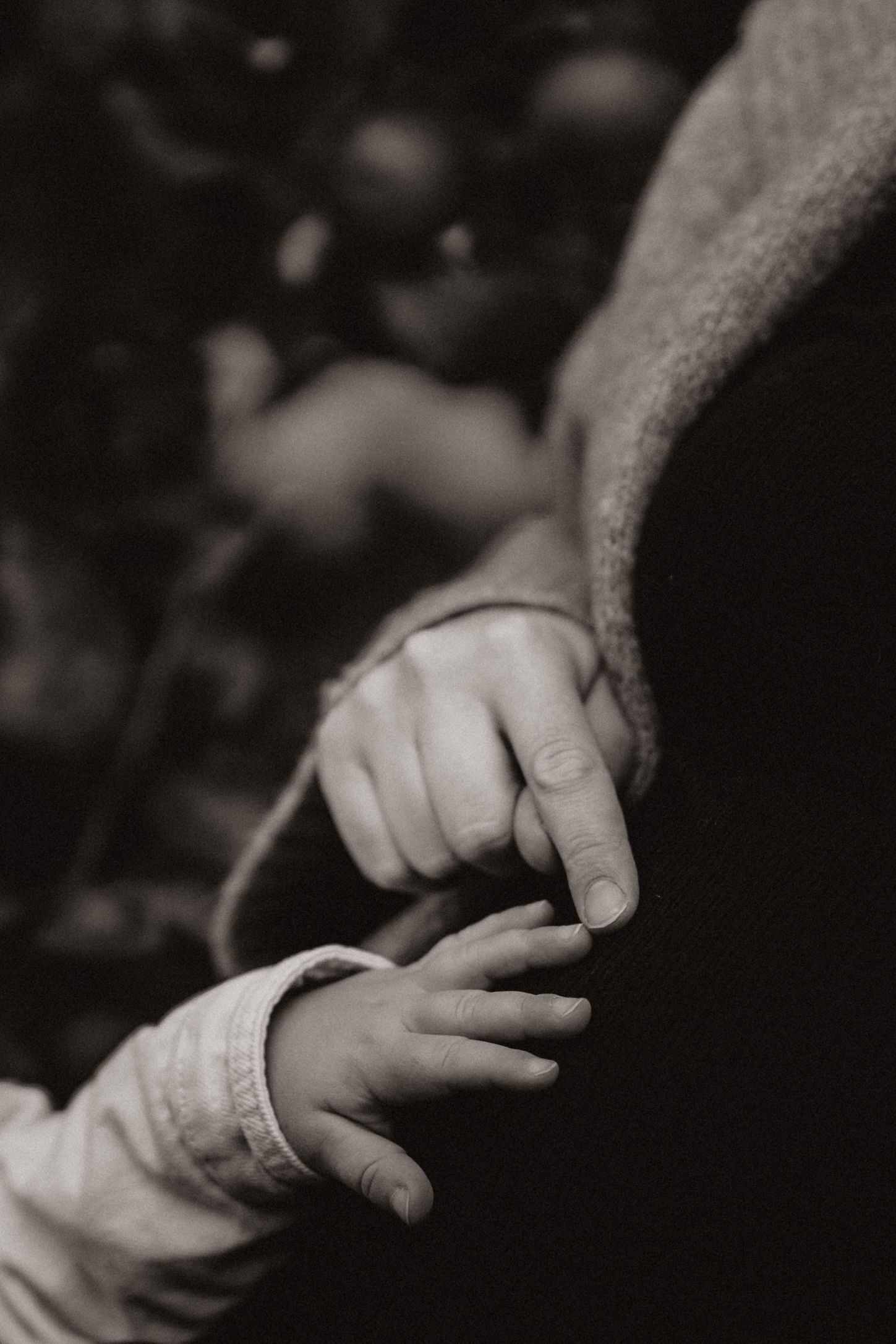 Parent and baby hold hands gently in black and white, symbolising new beginnings.