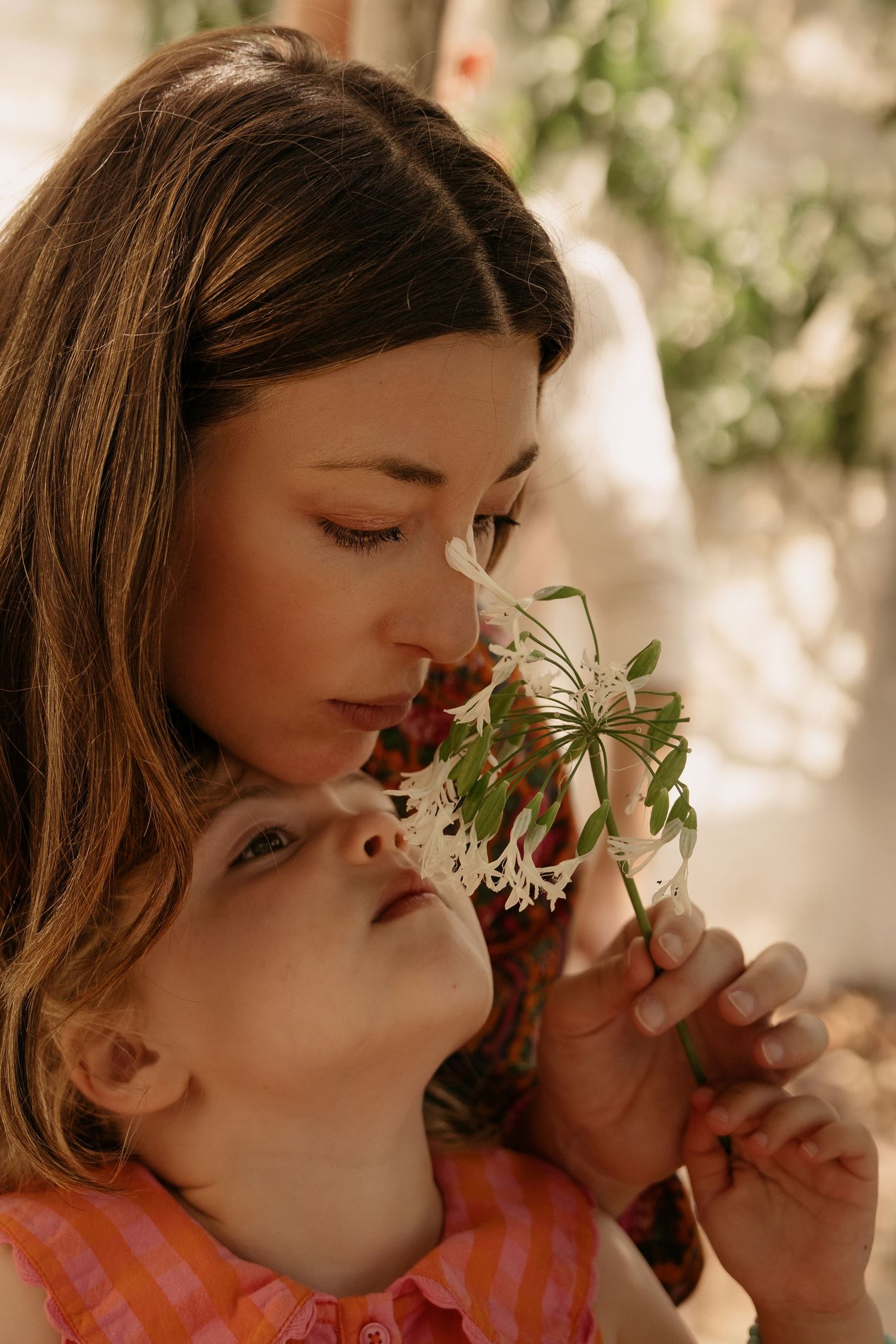 Mother holding a child while both smell a small plant in an orangery in The Midlands