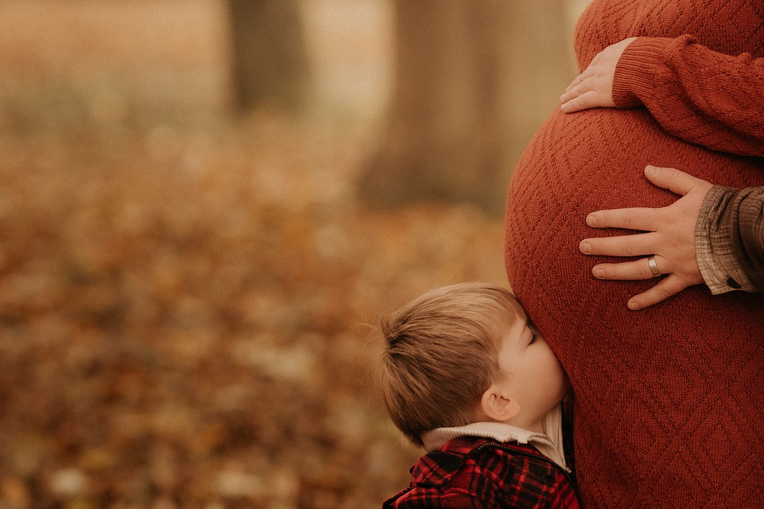 Child touching pregnant belly during an autumn maternity session in Swadlincote