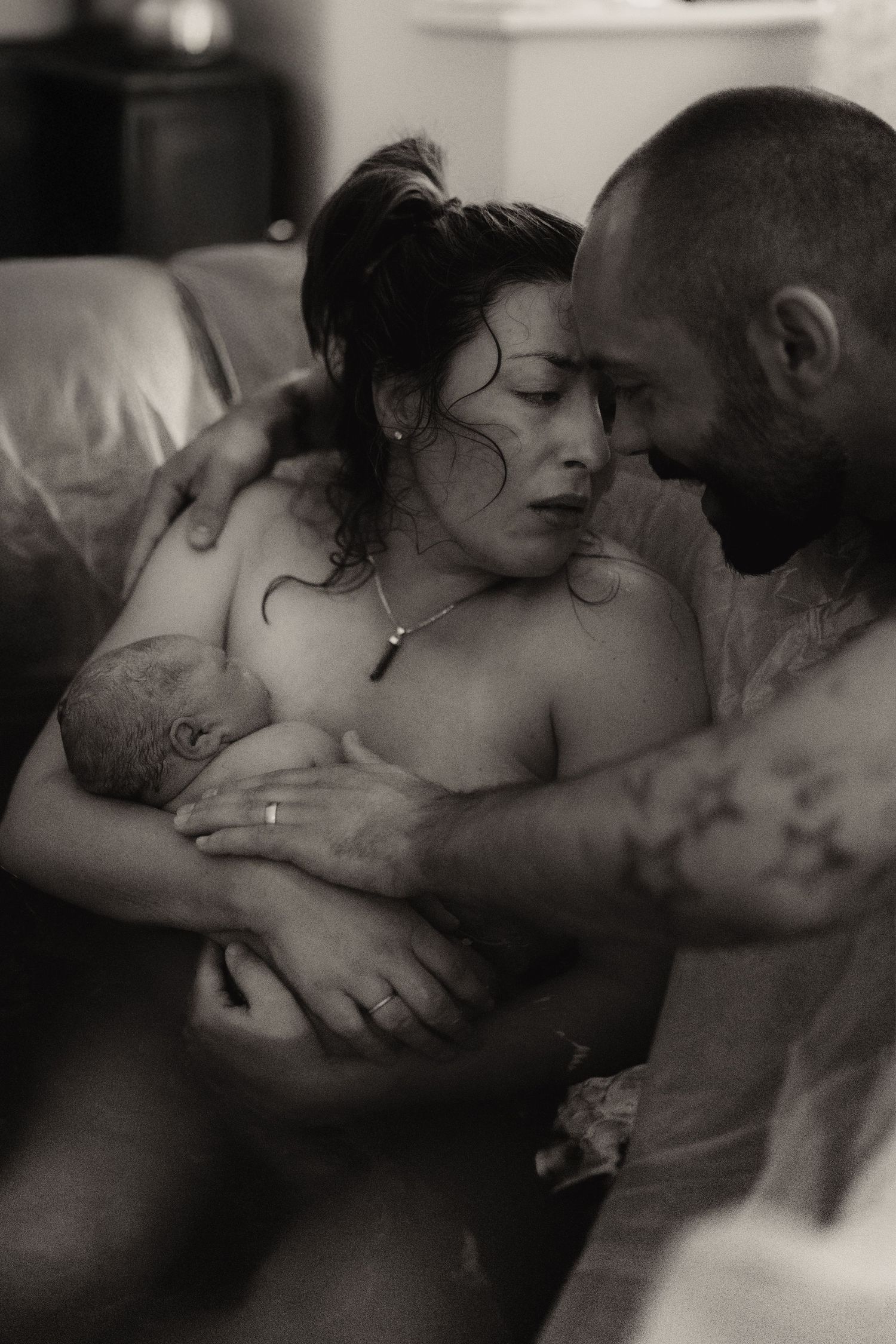 Parents holding their newborn moments after birth during an intimate documentary home birth photoshoot in Ashby de la Zouch