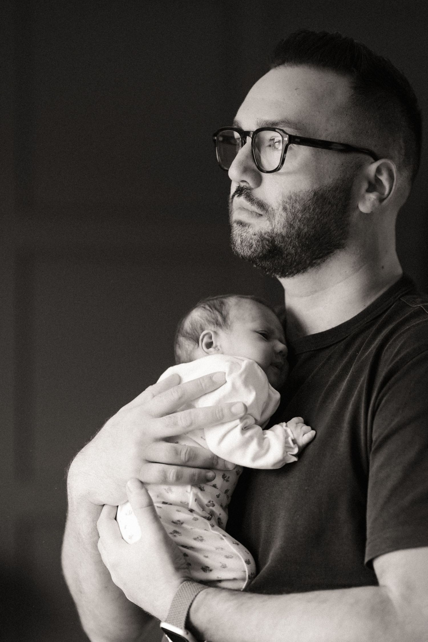 Father holding his newborn during a calm storytelling newborn photoshoot in black and white.