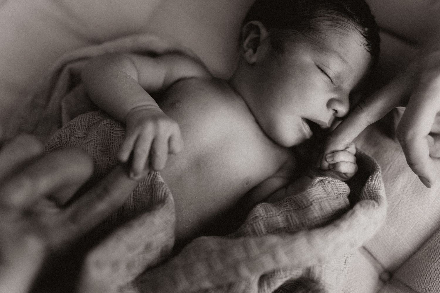 Sleeping newborn wrapped in blankets during a quiet storytelling newborn photoshoot in black and white.