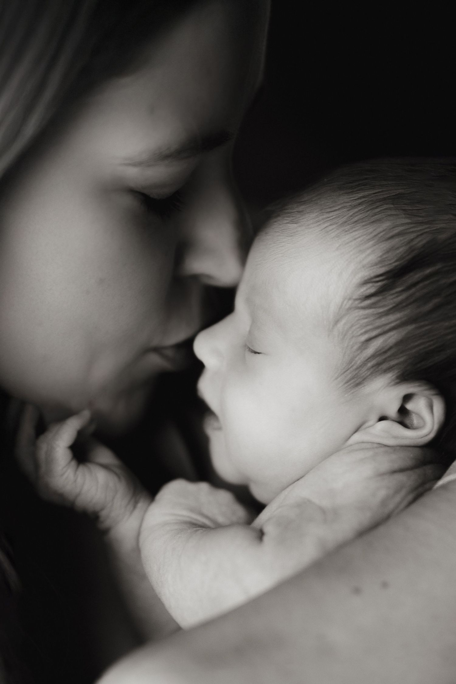 Mother holding her newborn against her chest during an intimate natural light lifestyle newborn photography session.