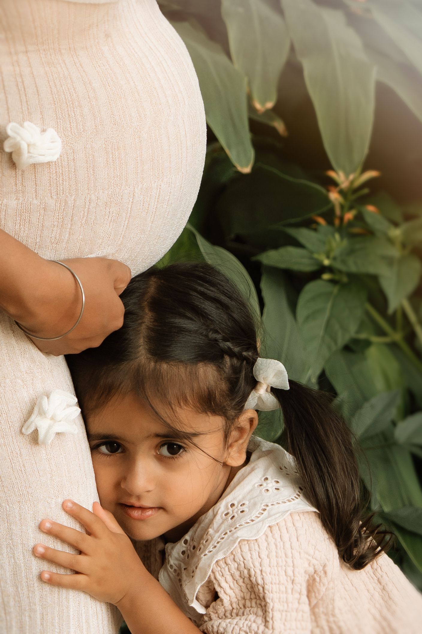 Little girl rests her cheek on her mother’s baby bump, capturing tender anticipation before birth.