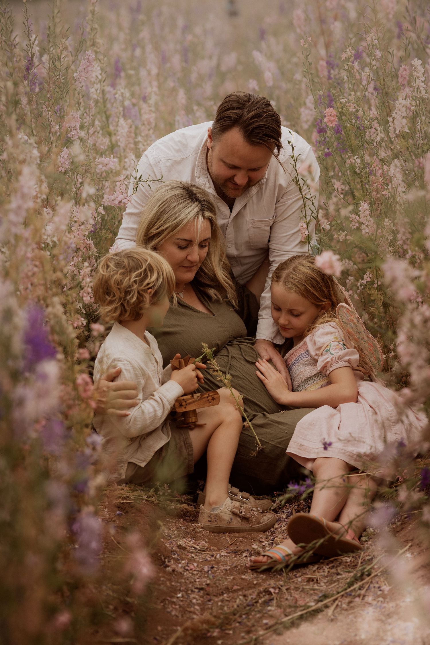 Family sits among delphiniums during a golden-hour Confetti Field photoshoot in Worcestershire.