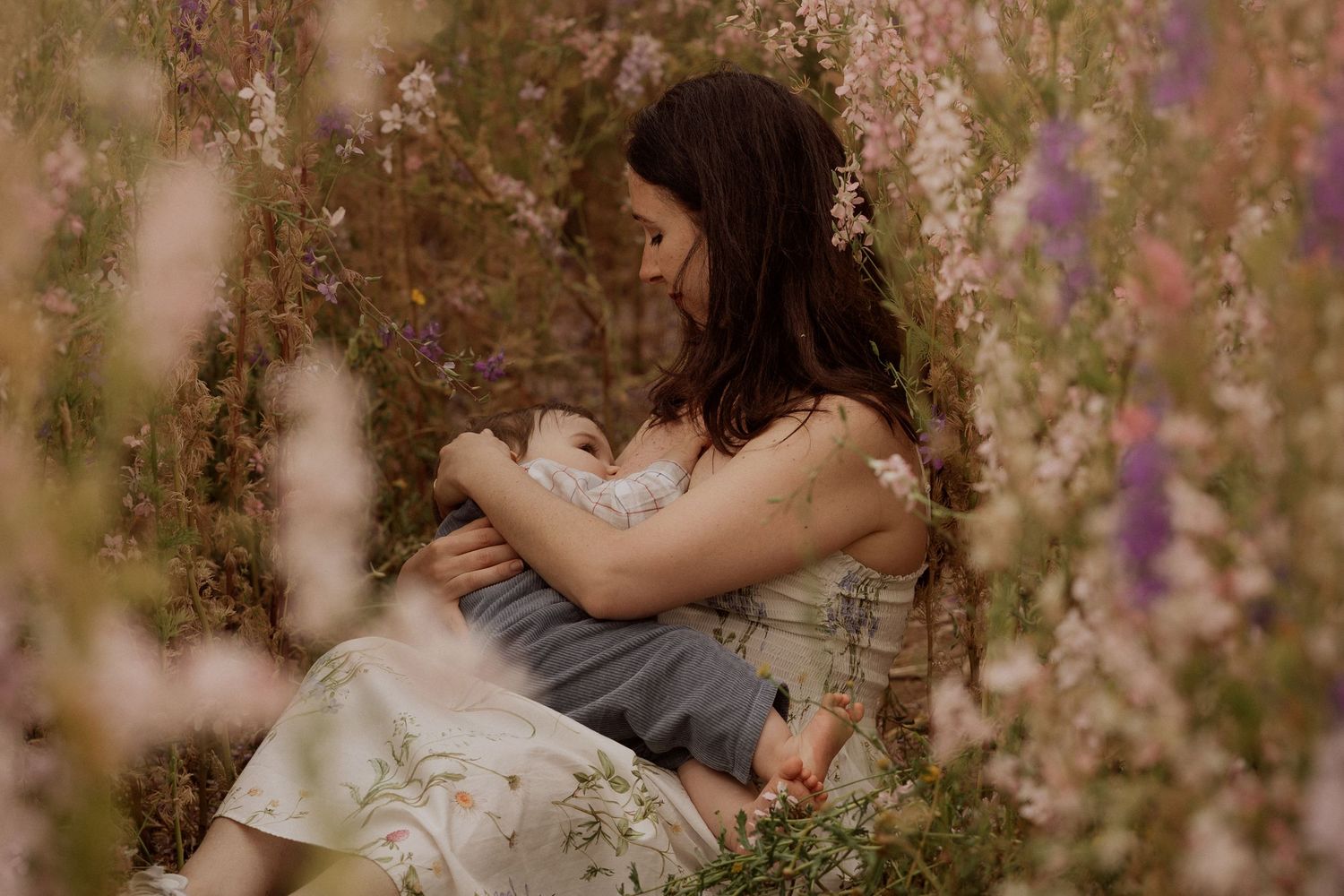 Family session at The Real Flower Petal Confetti Field - breastfeeding moment in the delphinium field