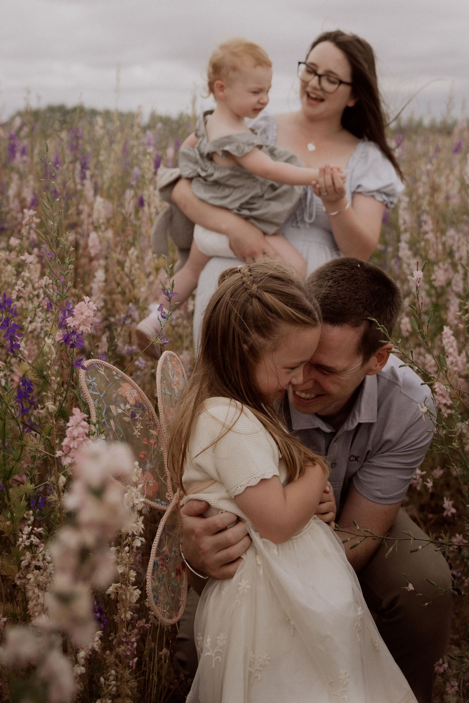 Family embracing together in a flower field during an outdoor documentary family photoshoot filled with connection in Confetti Field