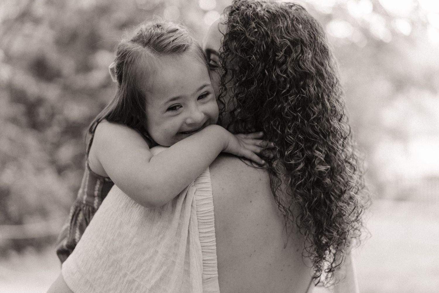 Child hugging a parent tightly during a joyful outdoor documentary maternity photoshoot