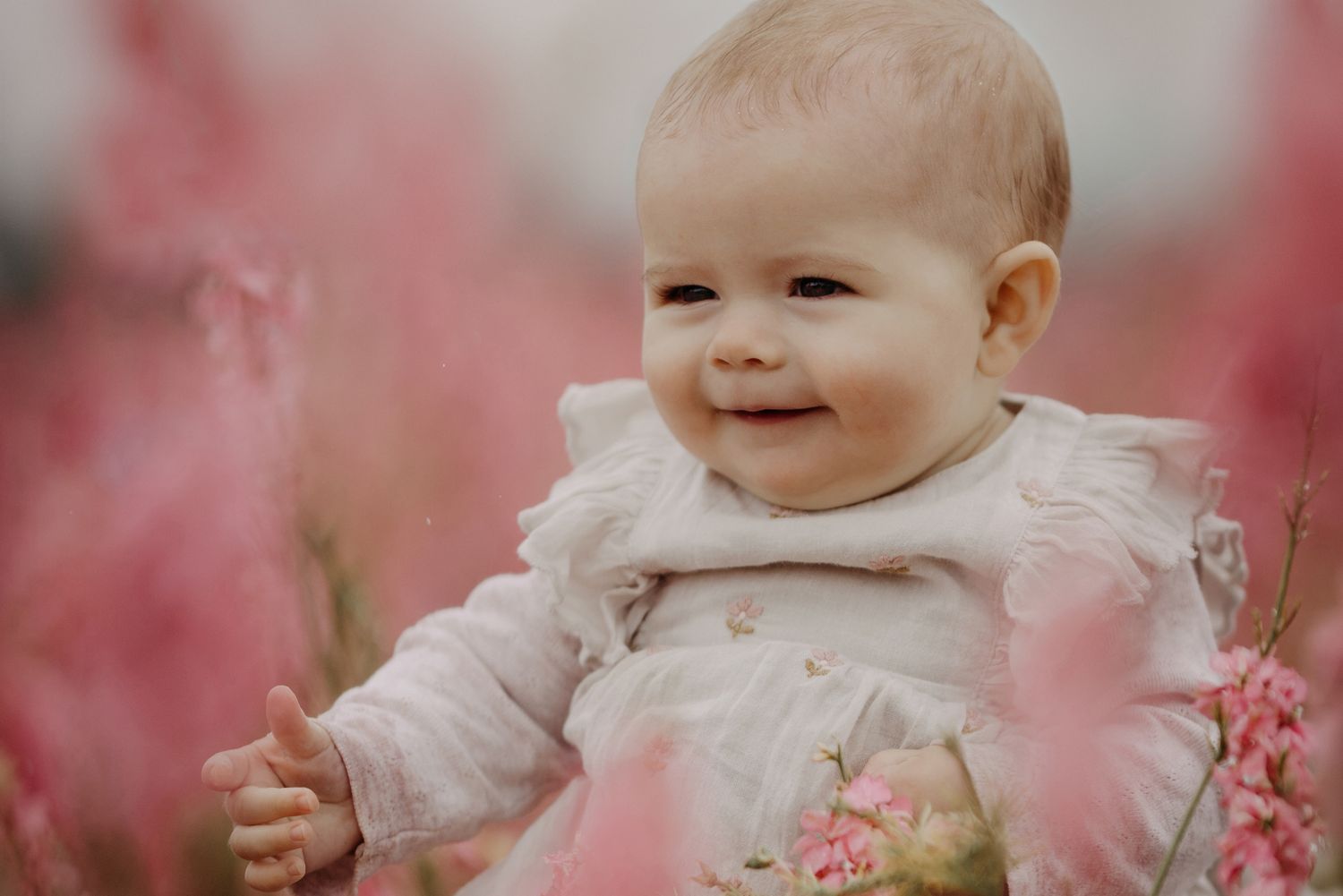 baby smiling in delphiniums during confetti field mini session