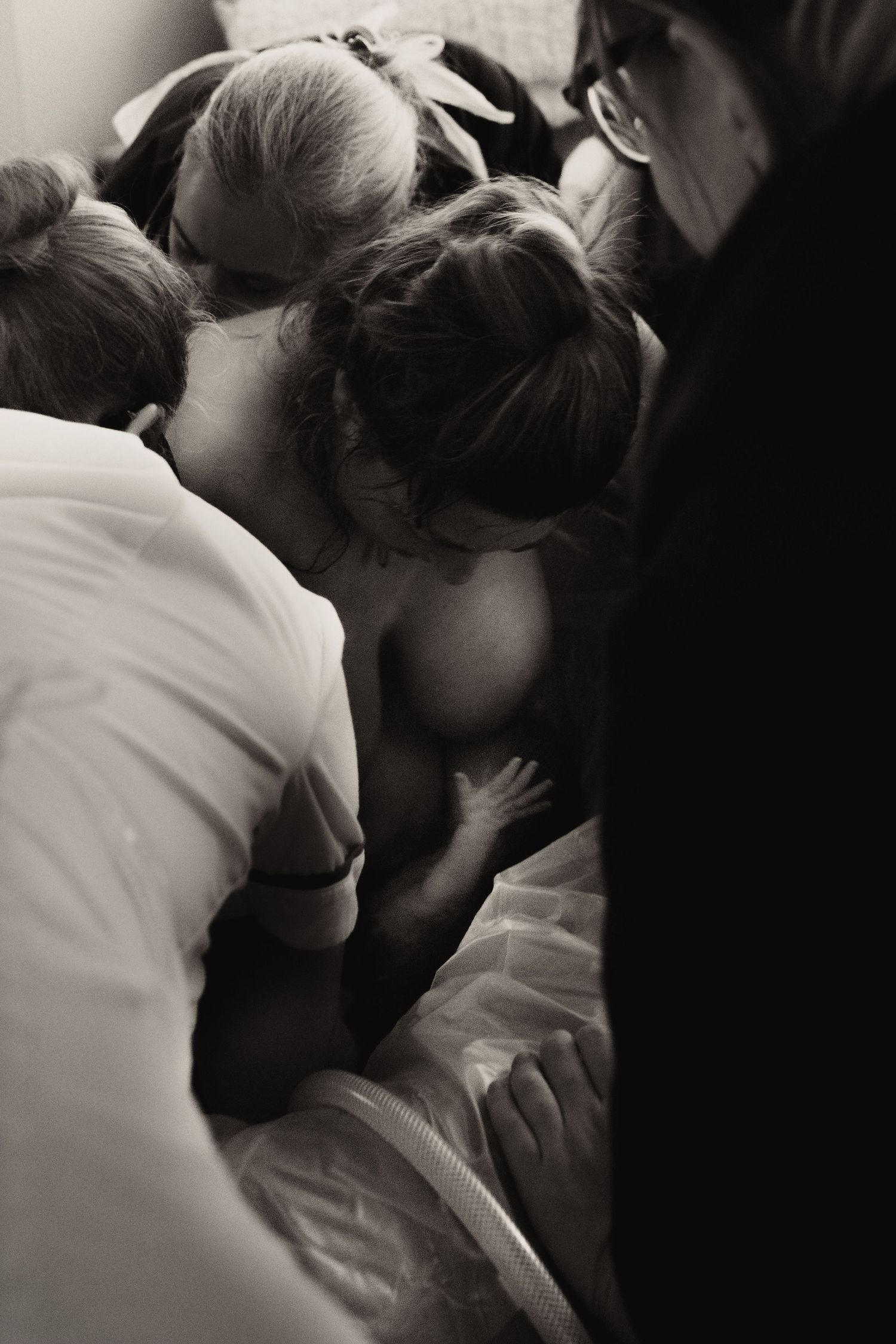 Support team surrounding a birthing parent during an intimate documentary home birth moment. birth photography