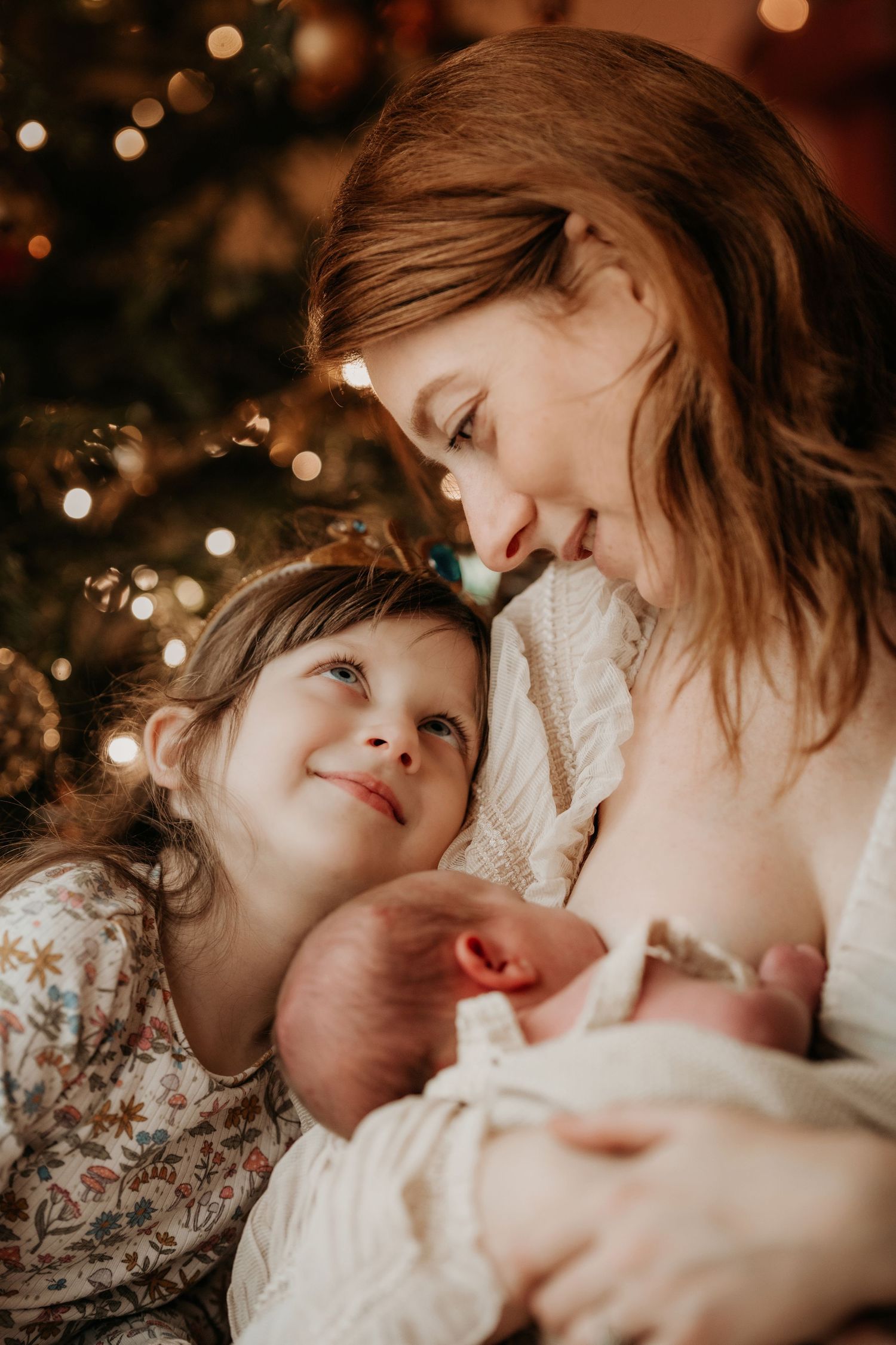 Mother and older child sharing a tender moment with their newborn during a cosy family lifestyle photoshoot in Asby de la Zouch