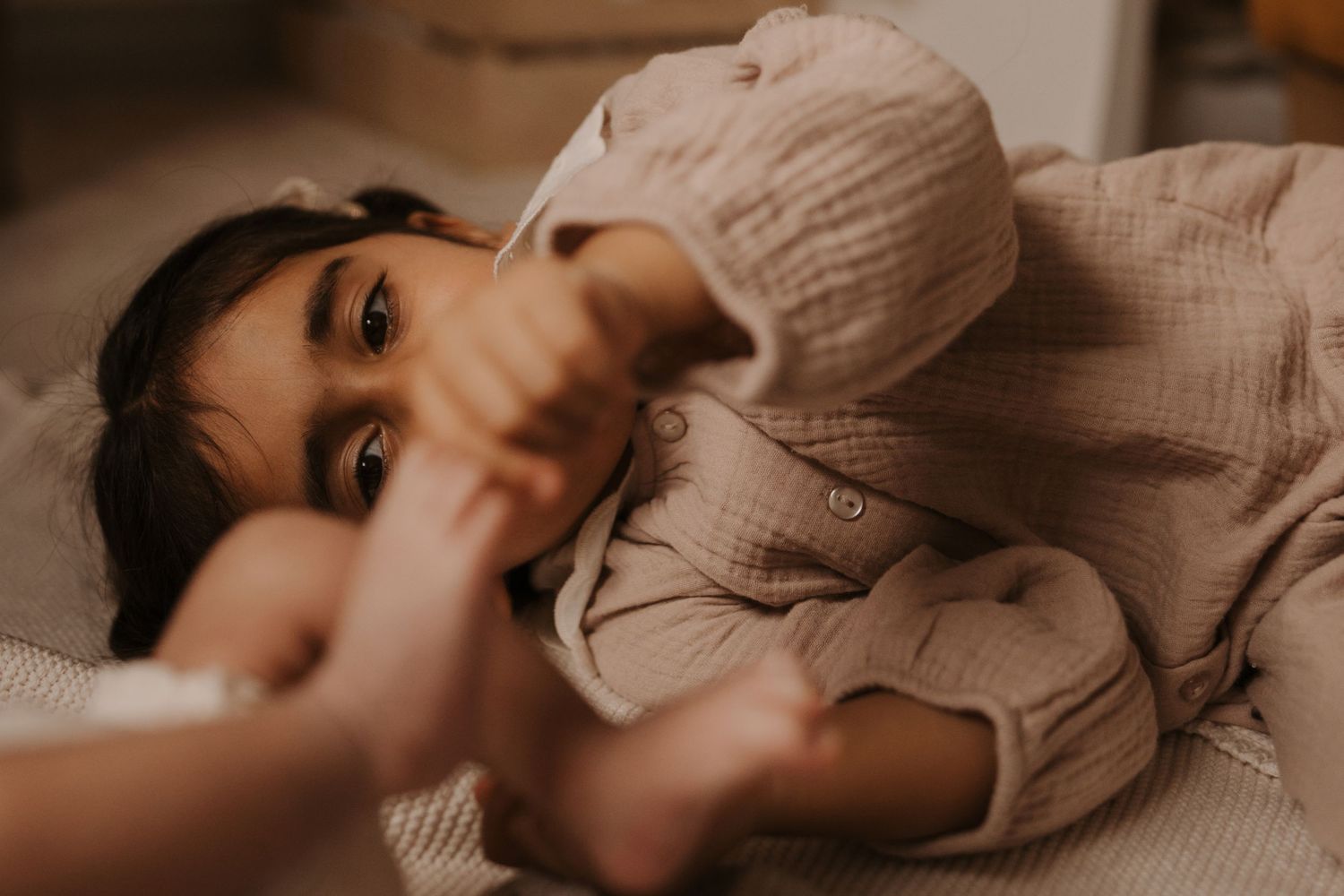 Baby playing with a parent’s hands during a relaxed lifestyle family photoshoot at home in Melbourne