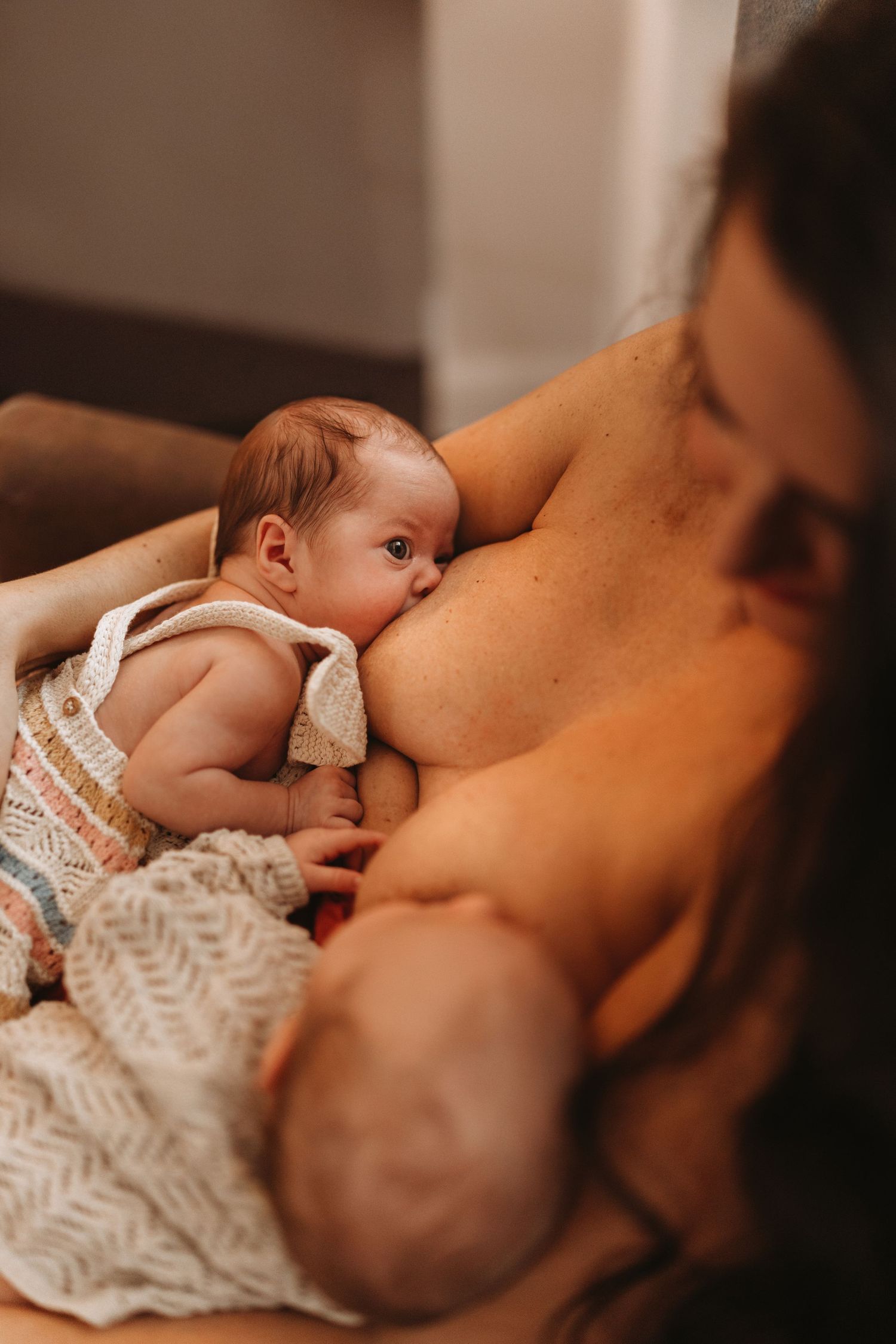 Newborn twins feeding peacefully in their mother’s arms during a quiet, at-home lifestyle newborn photoshoot with Soft Stories by Angela