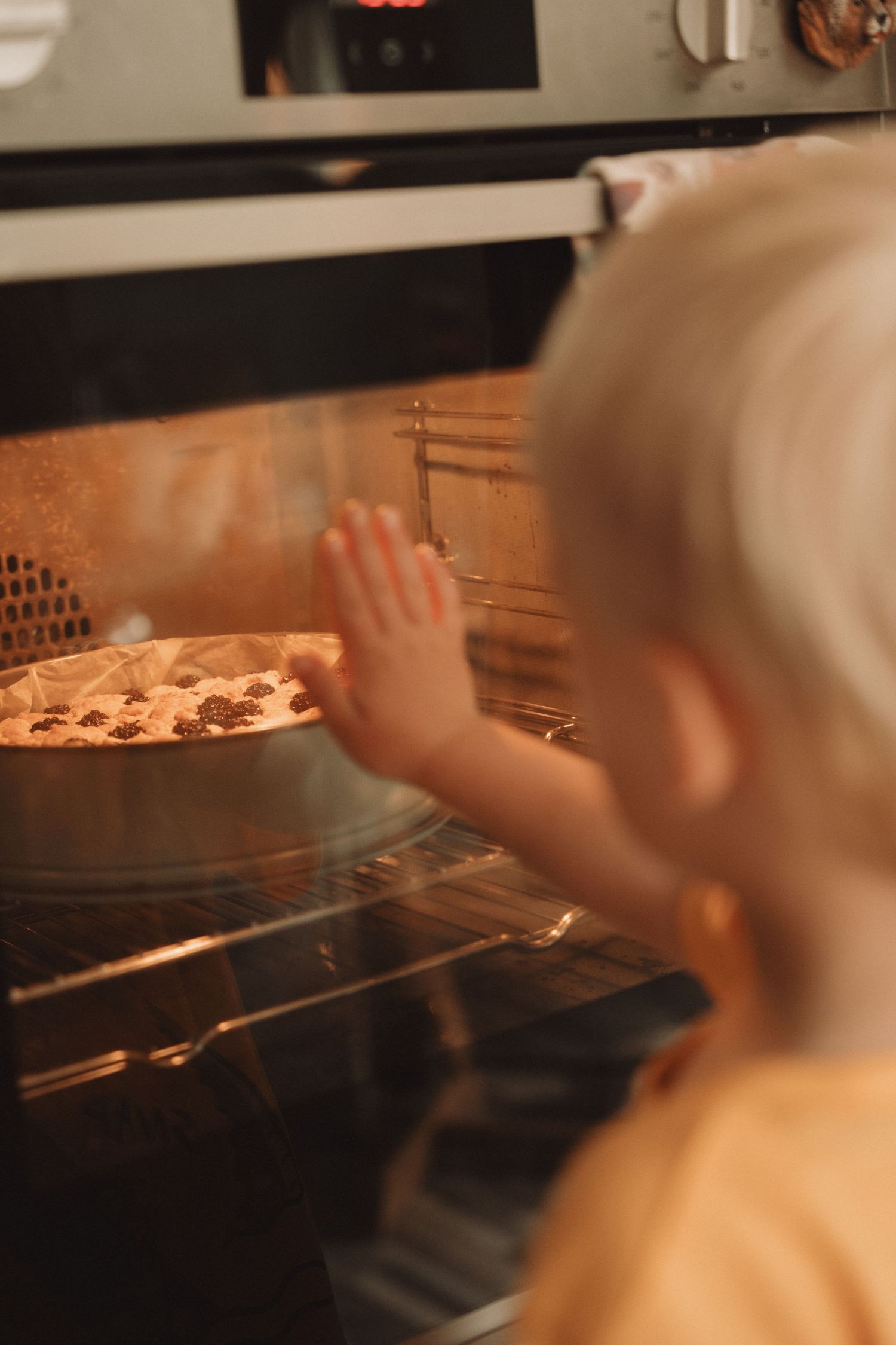 Curious toddler watching cookies bake through the oven door – storytelling moment of childhood wonder.