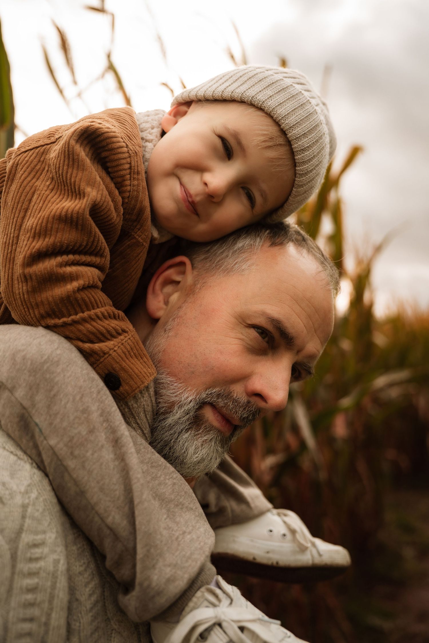 Little boy rests his head on his dad’s shoulder during a pumpkin patch photoshoot in Ashby-de-la-Zouch.