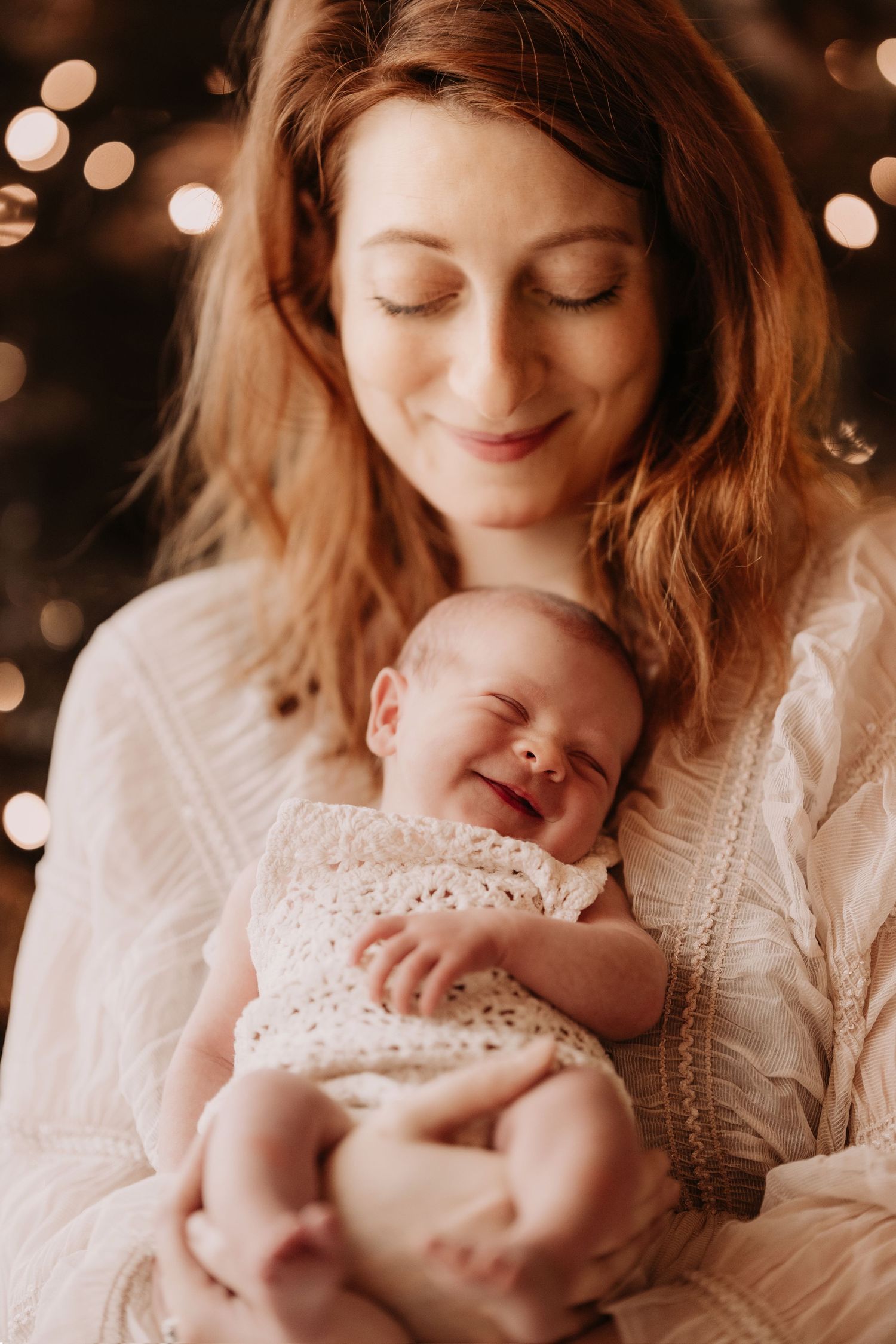 Mother and newborn smiling softly in a warm, intimate family photoshoot in Asby de la Zouch