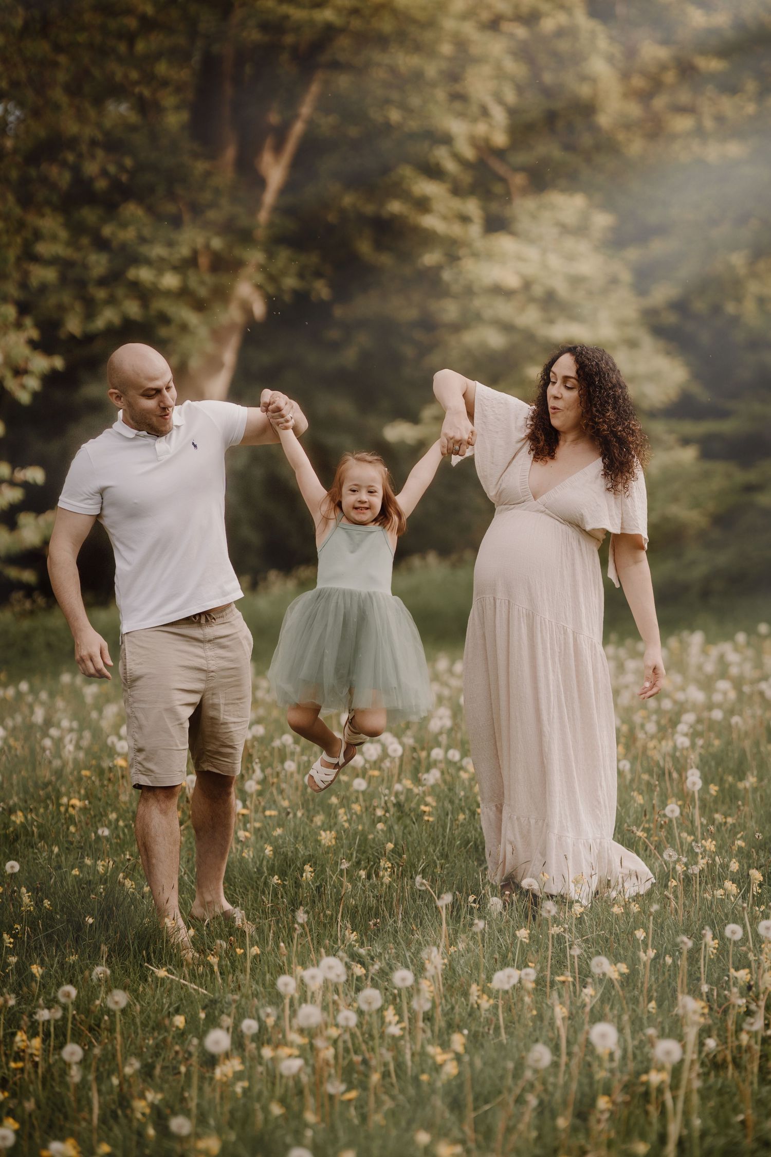 Family runs through a sunny meadow, celebrating togetherness during a maternity photoshoot in Swadlincote