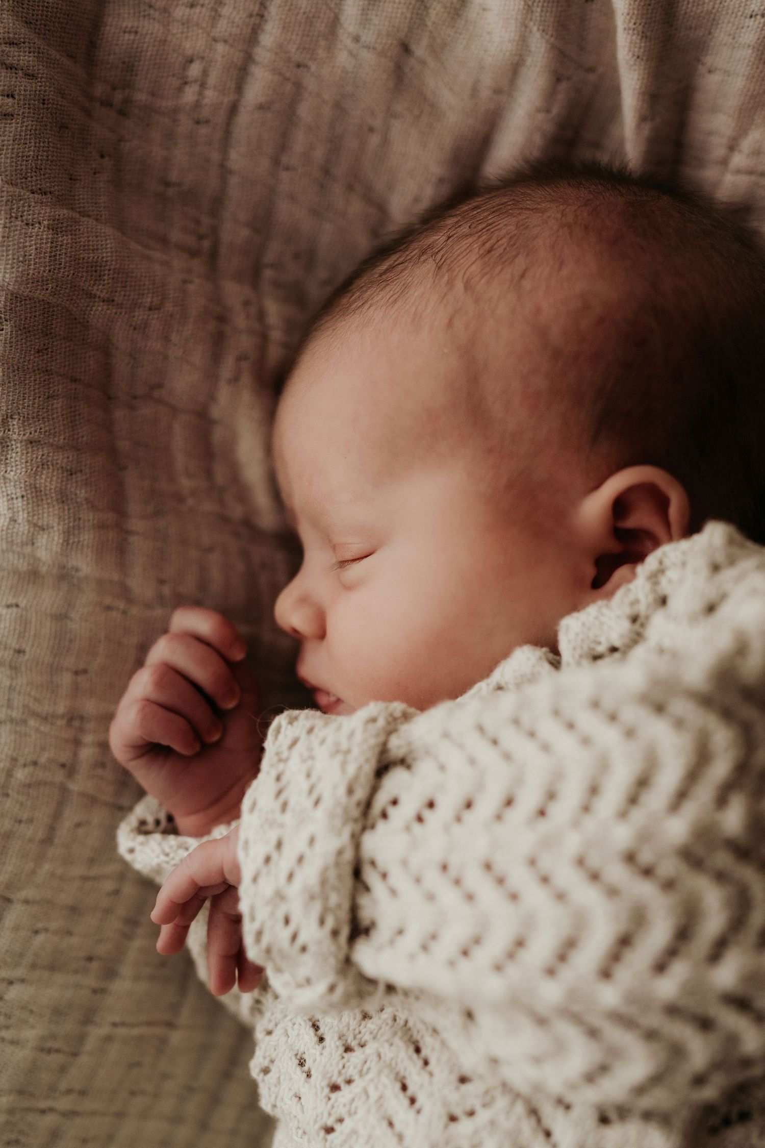 Newborn sleeping in a knitted outfit during a natural light lifestyle newborn photography session in Asby de la Zouch