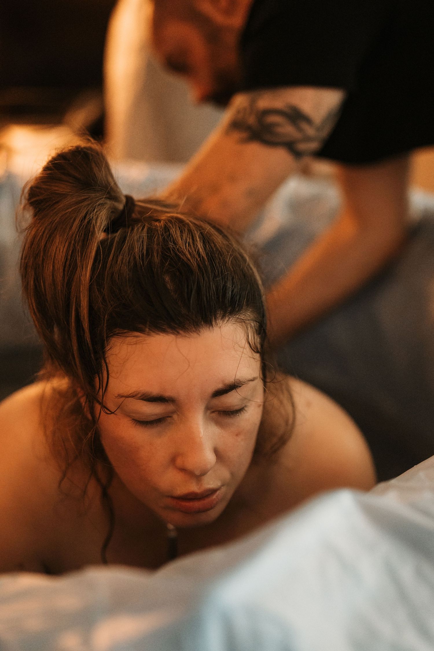 Birthing parent breathing through a contraction with partner support during a documentary home birth.