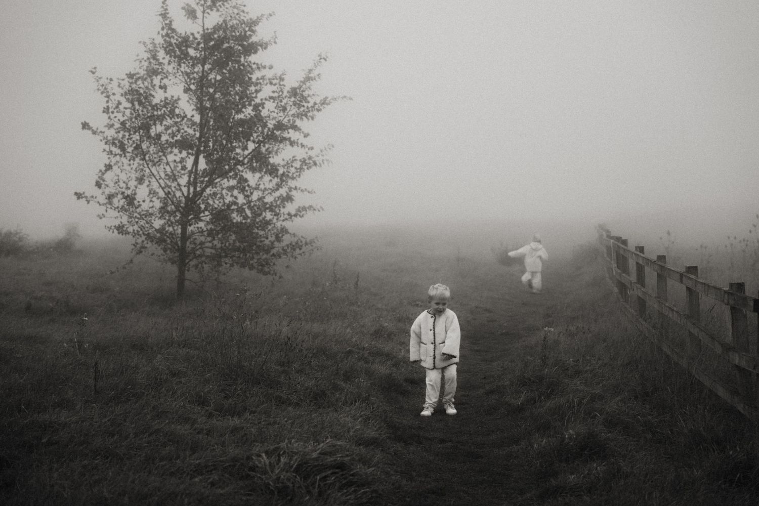 Children walk through soft morning fog on a quiet path during a moody outdoor family photoshoot in Swadlincote