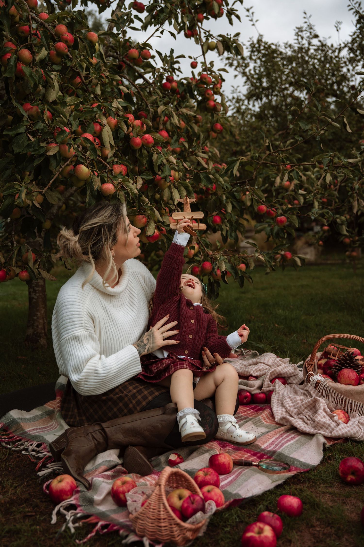 Mum and baby sit under apple trees during a cozy autumn orchard photoshoot in Tamworth