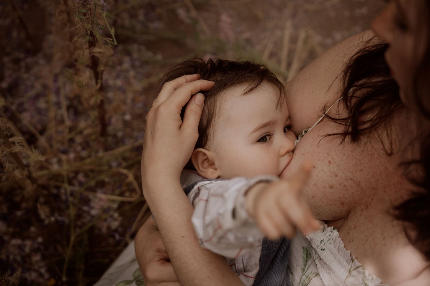 Parent kissing their baby outdoors during a gentle documentary family photoshoot. in Confetti Field