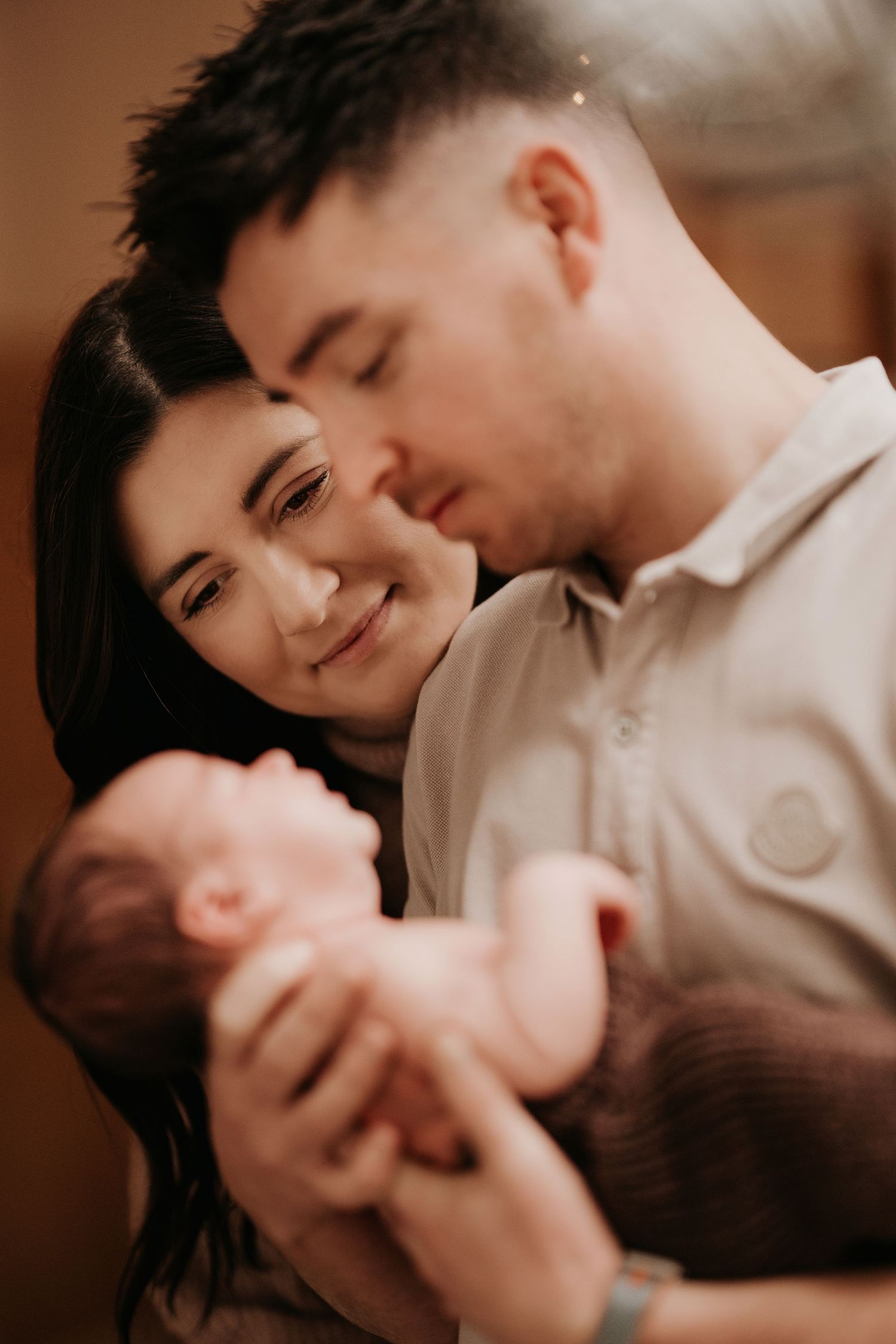 Parents admiring their baby during an intimate storytelling newborn photoshoot filled with connection, in Hinckley