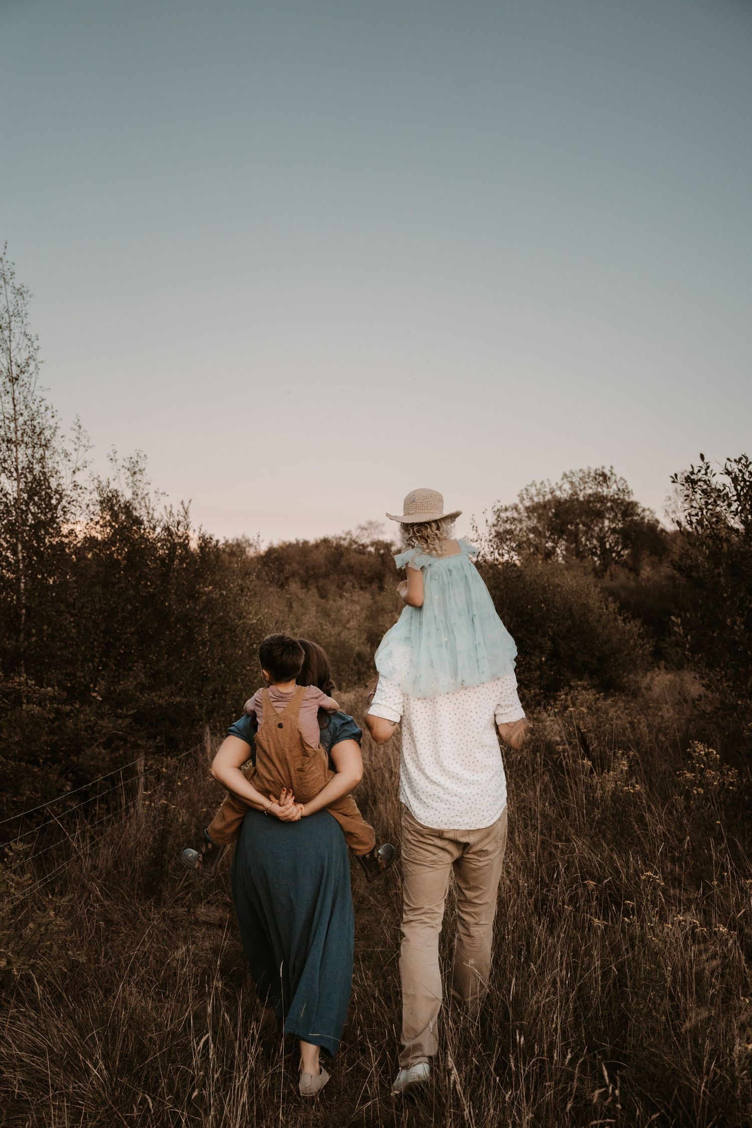 Family walking through golden fields at sunset – storytelling by Swadlincote photographer Angela Palka