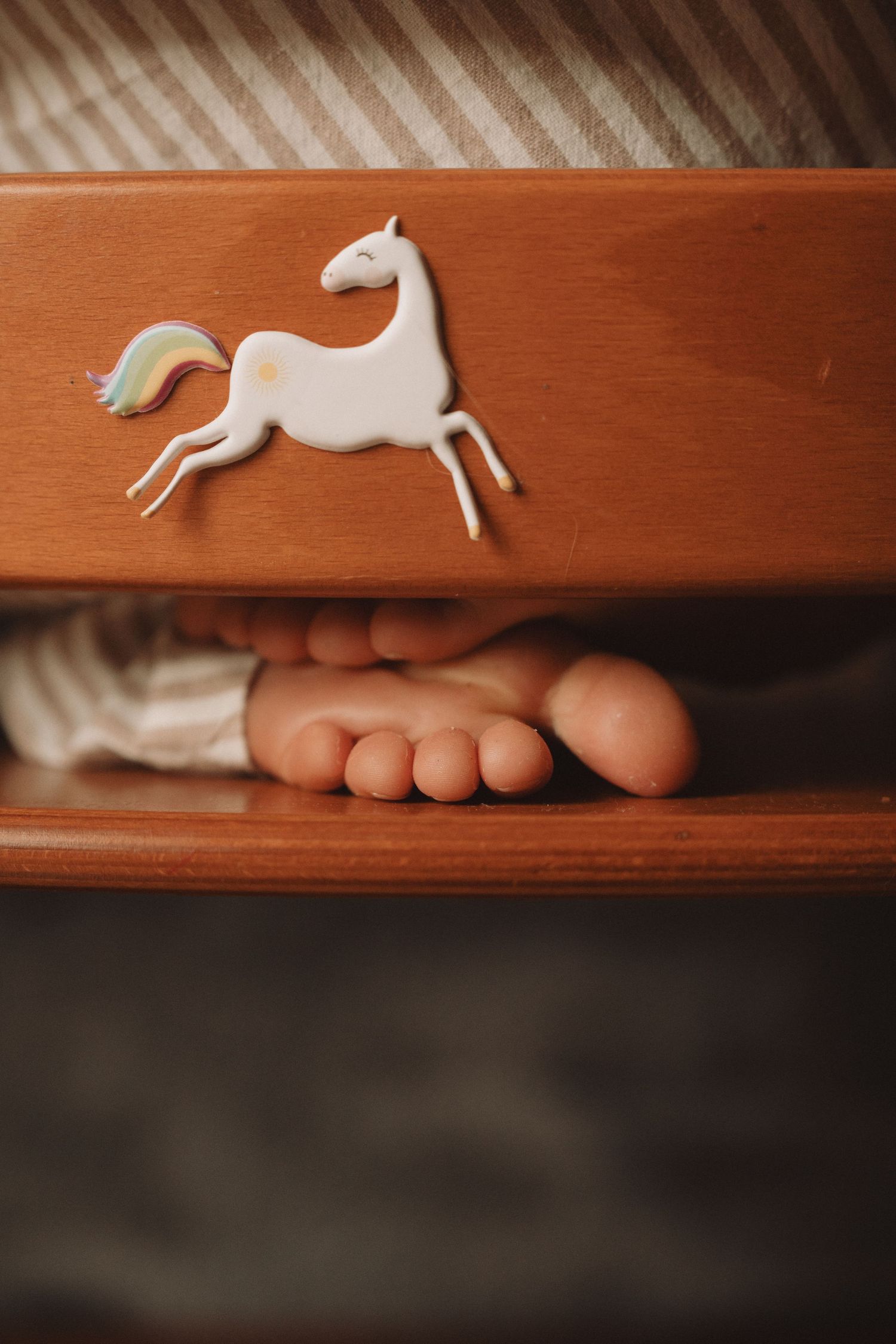 Little bare feet resting beside a white toy horse – tender storytelling details captured by Midlands photographer.