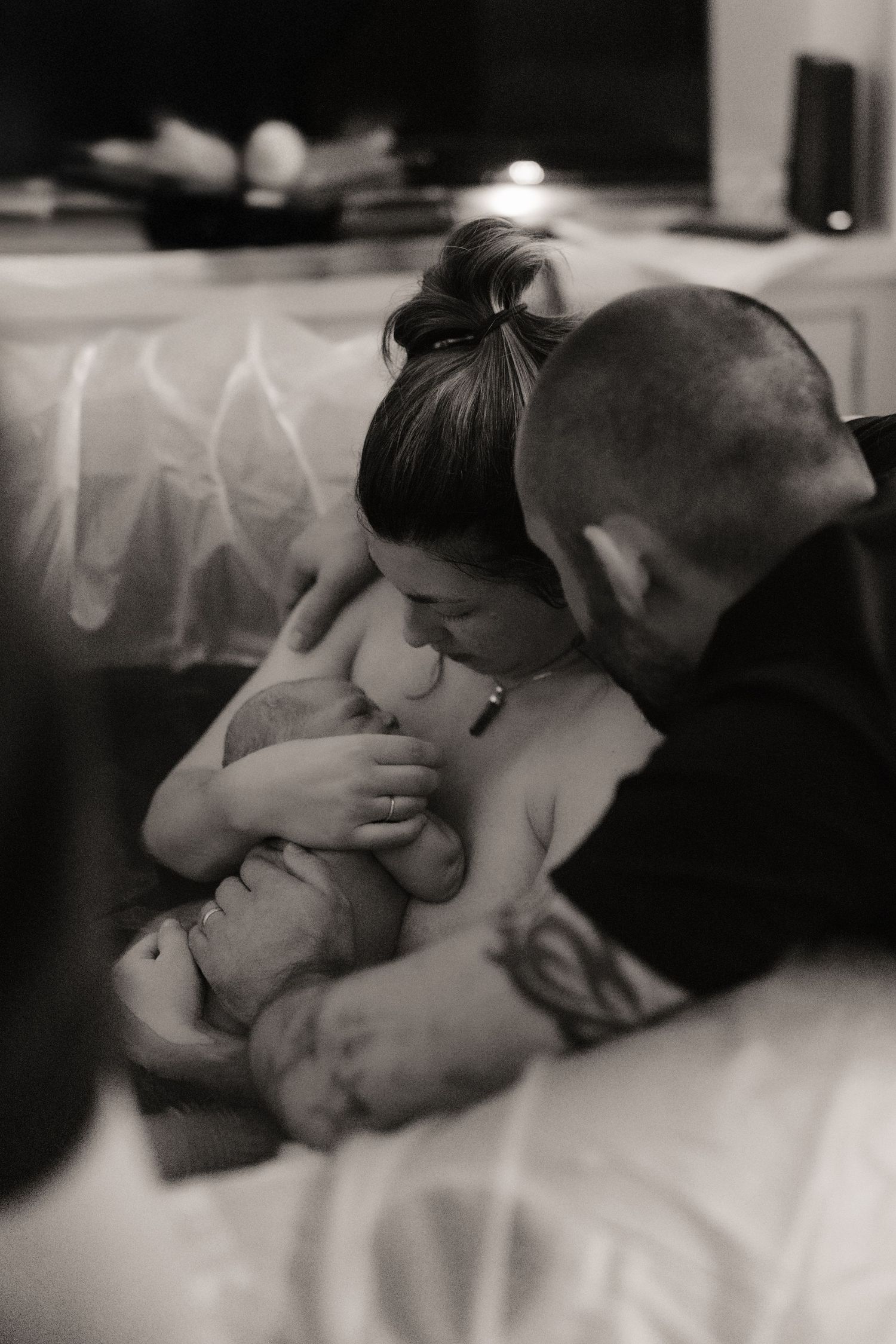 Parents holding their newborn moments after birth during an intimate documentary home birth session.