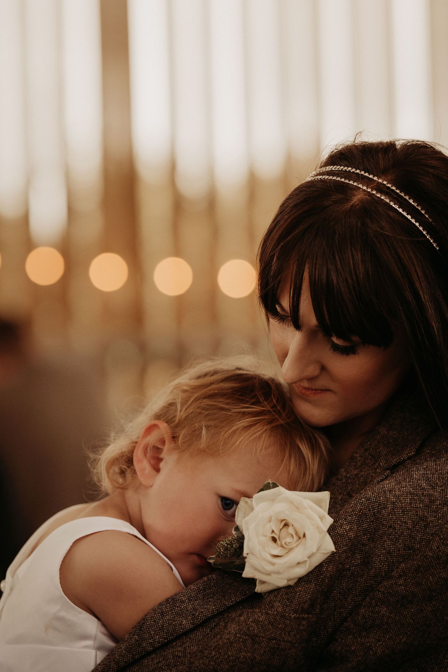 Parent holding a sleepy child with a flower tucked in their clothing during a tender moment.
