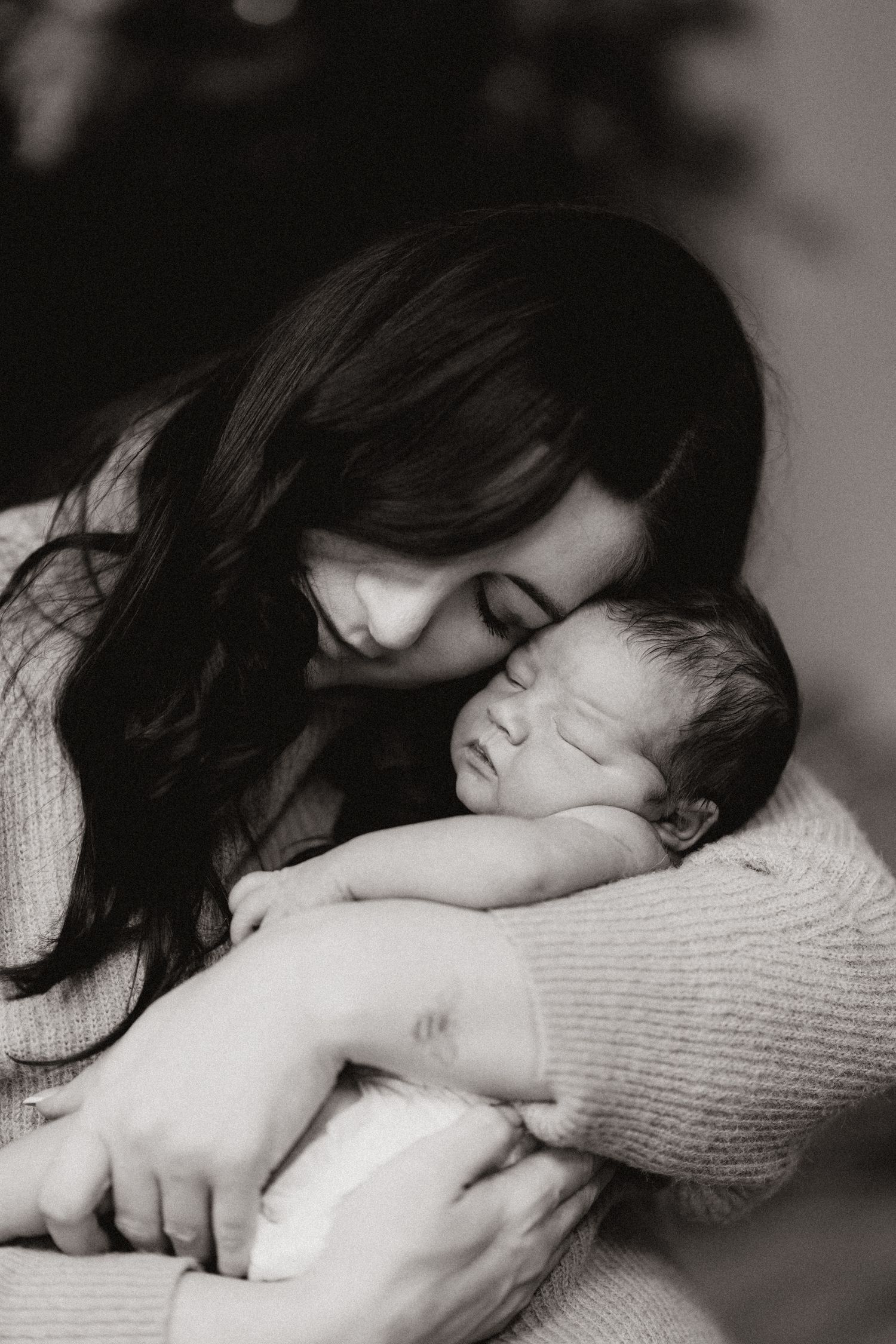Mother holding her newborn close during an intimate in-home lifestyle newborn photography session.