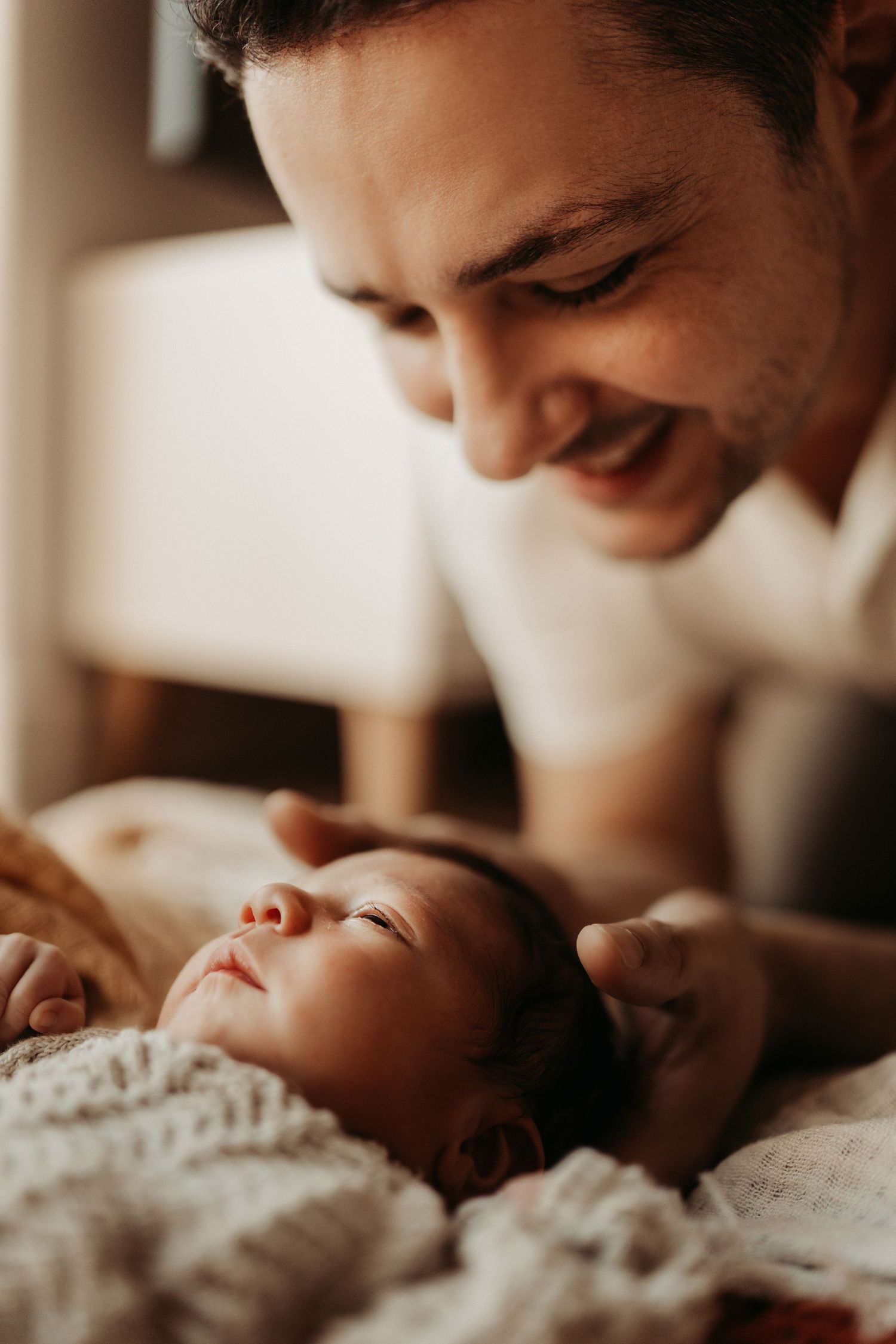 Father watching his sleeping newborn during a calm lifestyle newborn photoshoot at home in natural light in Stoke on Trent