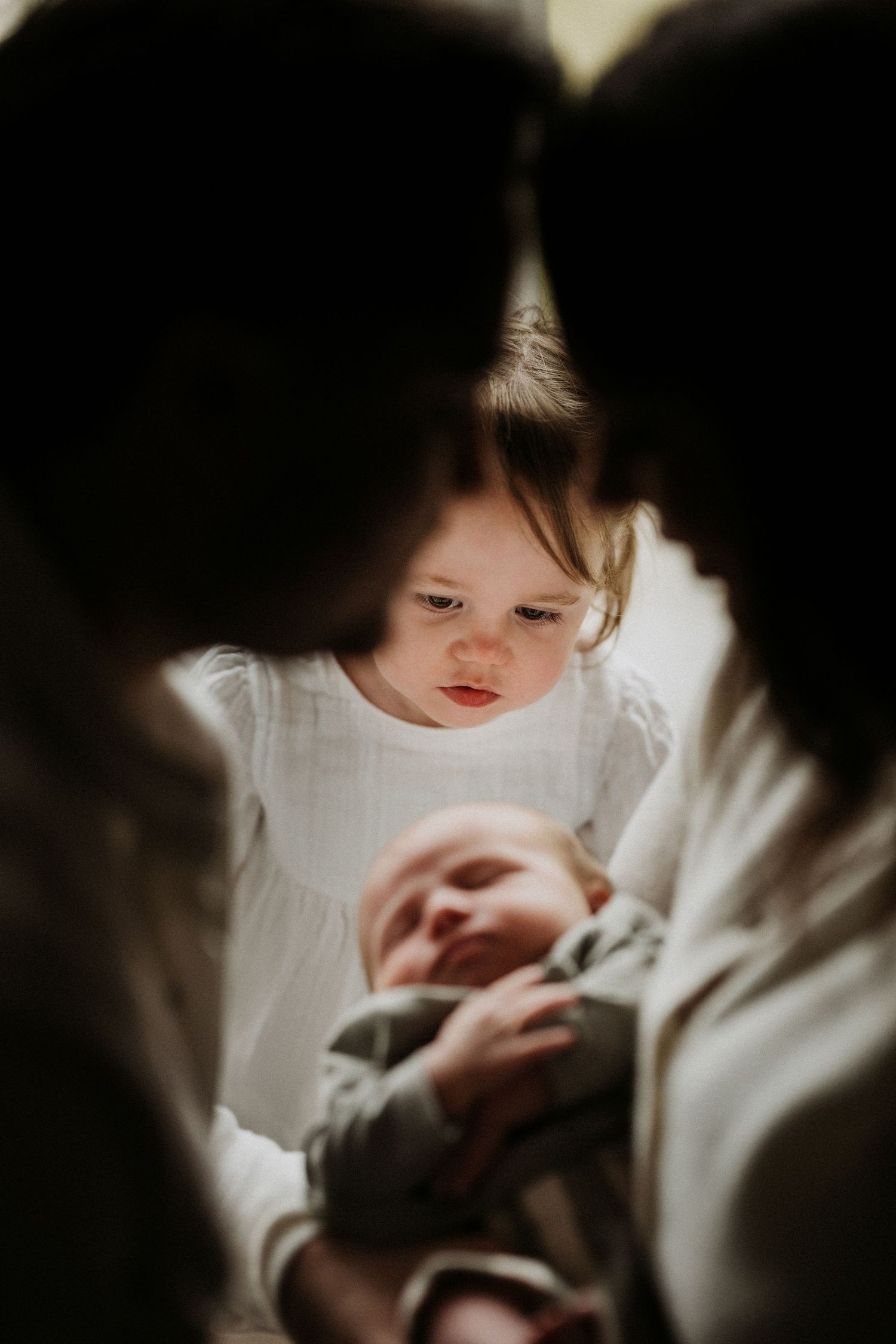 Parents gazing at their newborn between them during a tender storytelling newborn photoshoot in Tamworth
