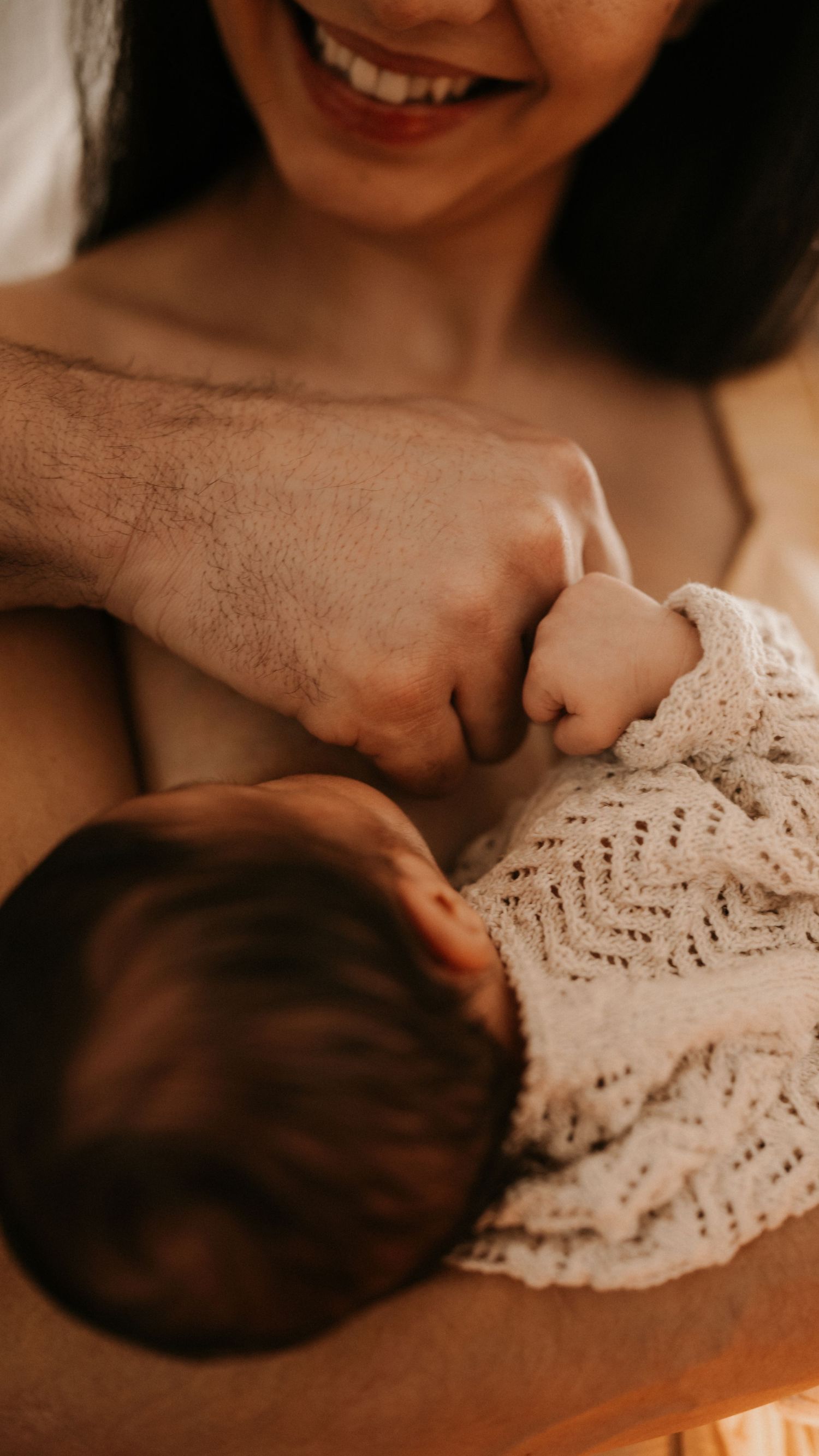 Mother holding her newborn close during a relaxed lifestyle newborn photoshoot at home.