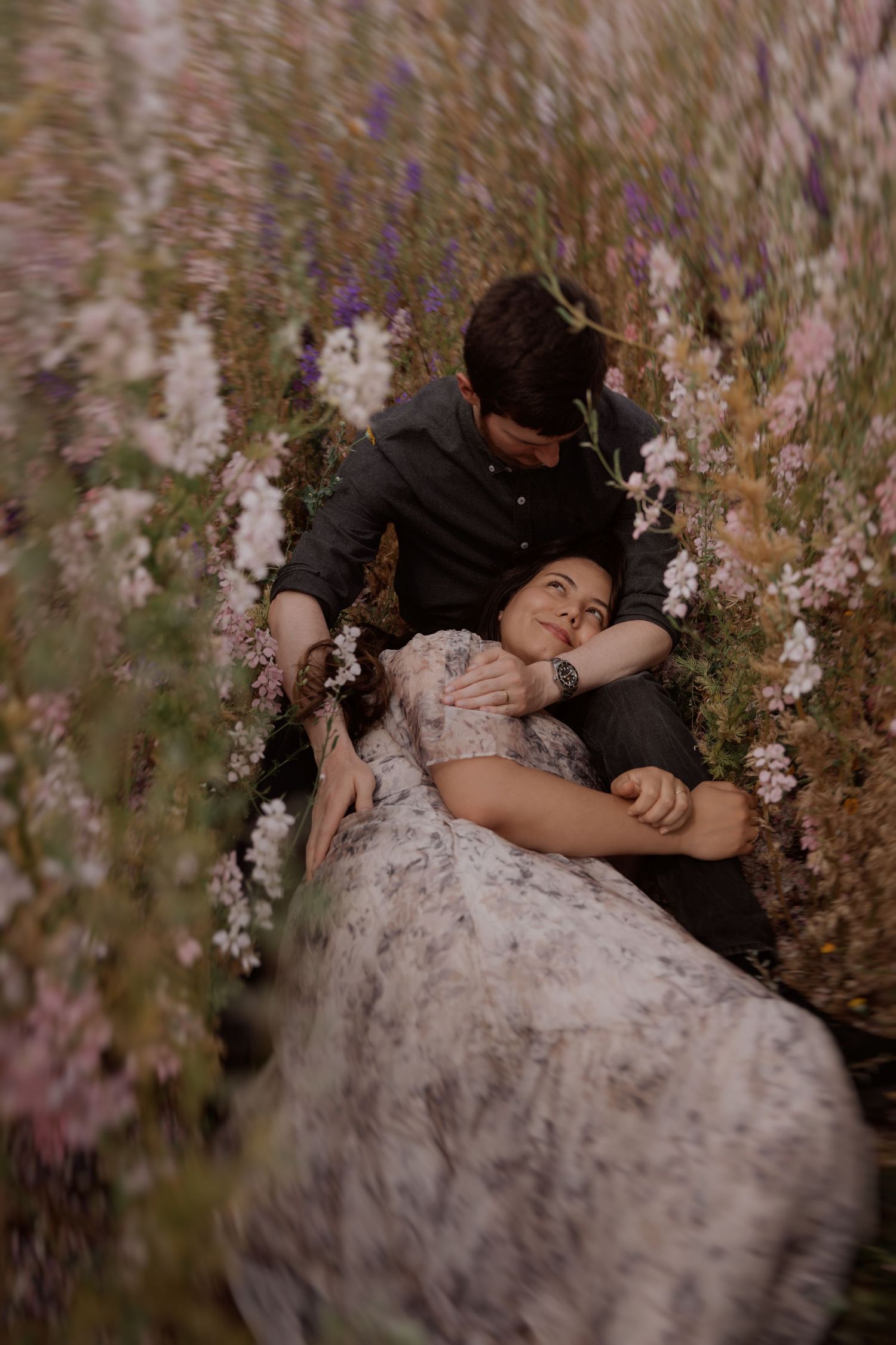 A couple resting together in a wildflower field, a calm and intimate moment captured naturally by Soft Stories by Angela