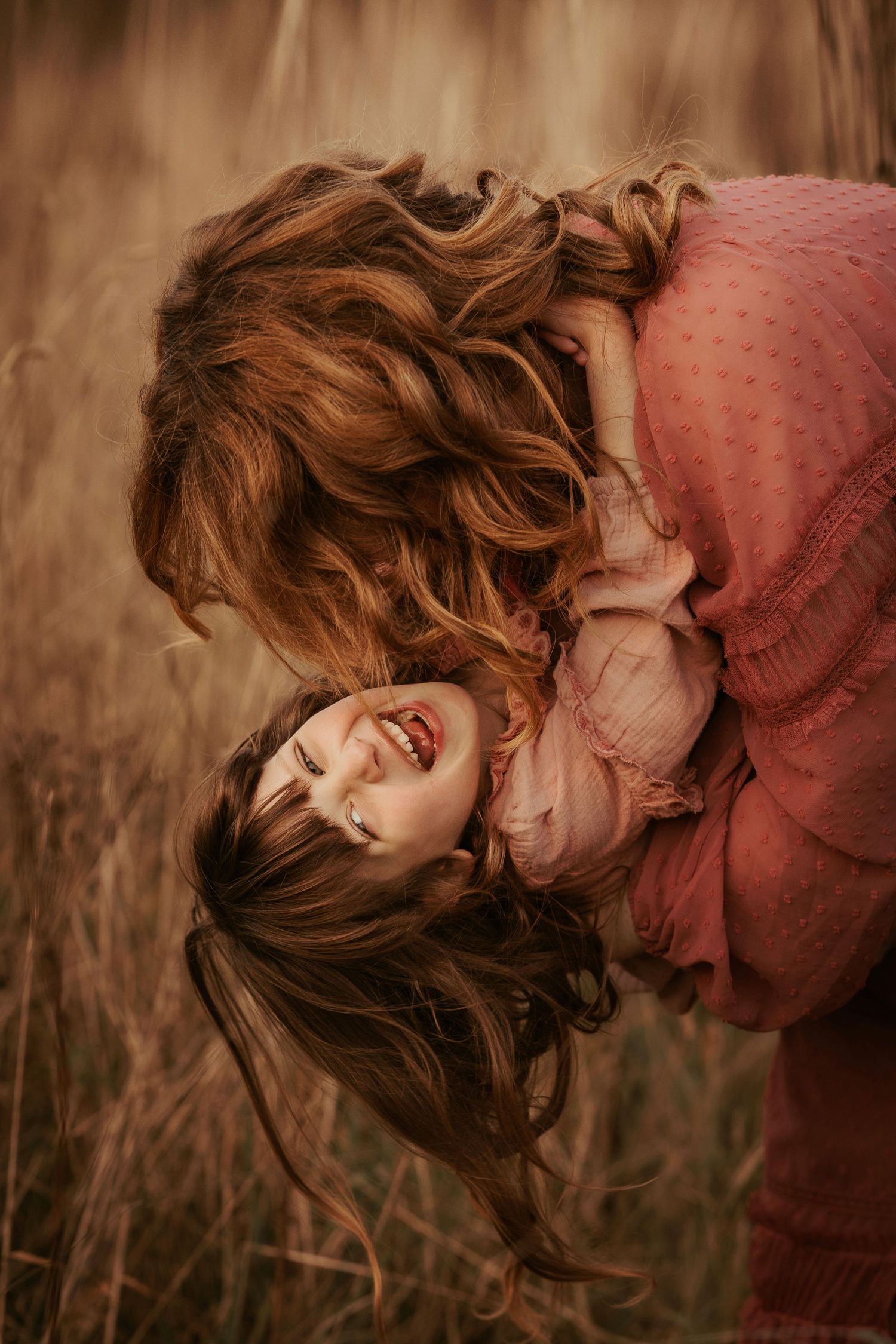 Mother and daughter laughing together in a field during a warm documentary family photoshoot in Asby de da Zouch