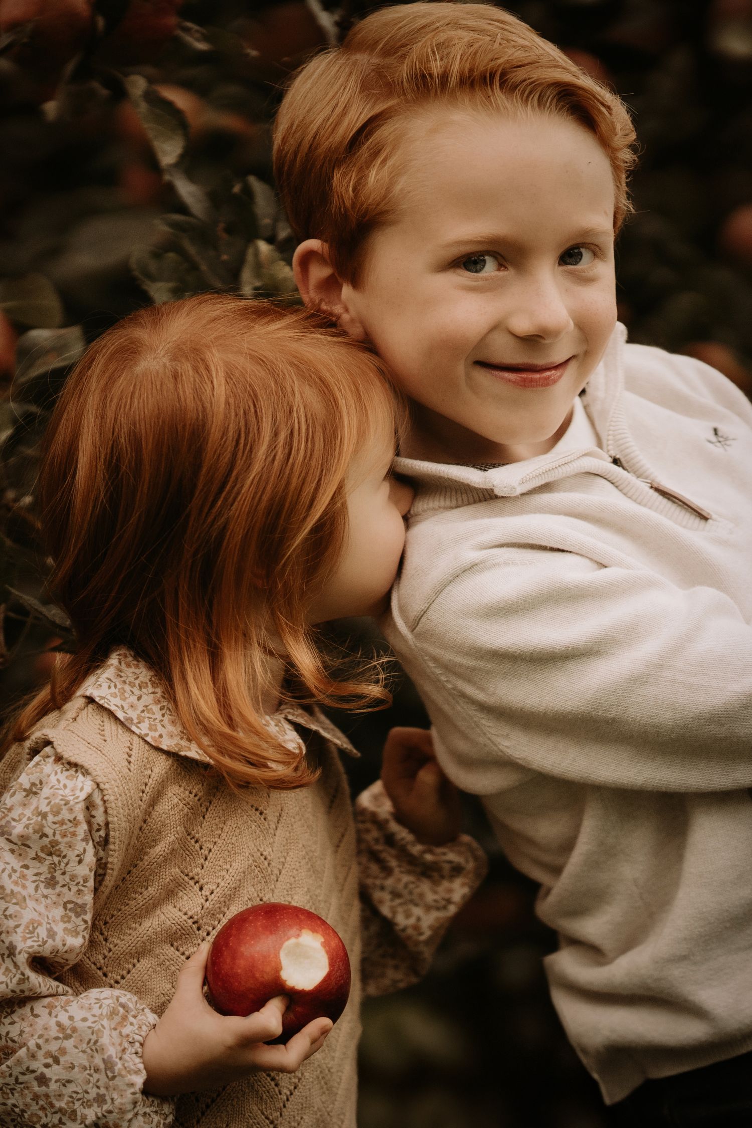 Siblings sharing a quiet moment in an orchard during a candid outdoor documentary family photography session.