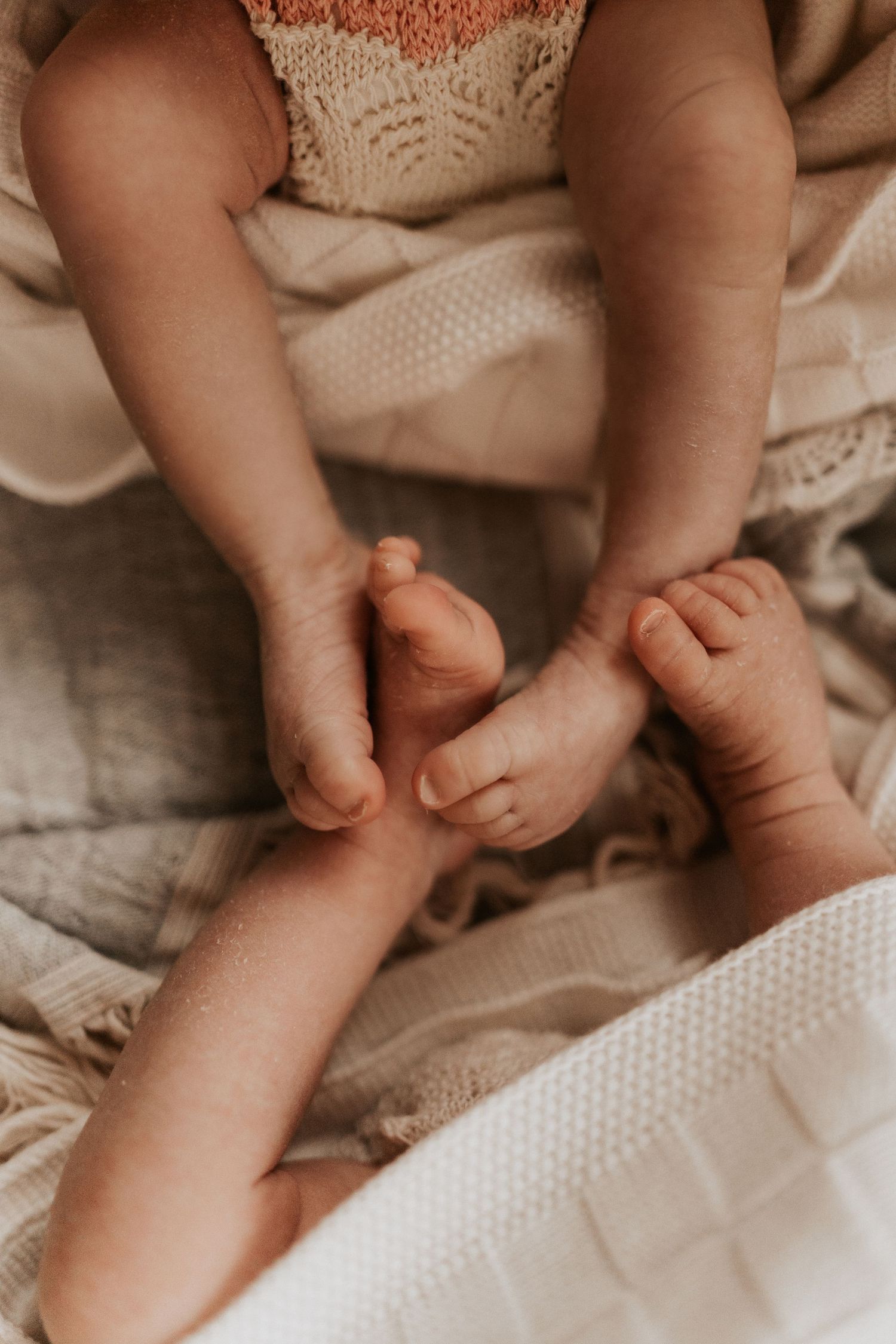 Tiny baby feet resting in parents’ hands, captured during a gentle storytelling newborn twins photoshoot.