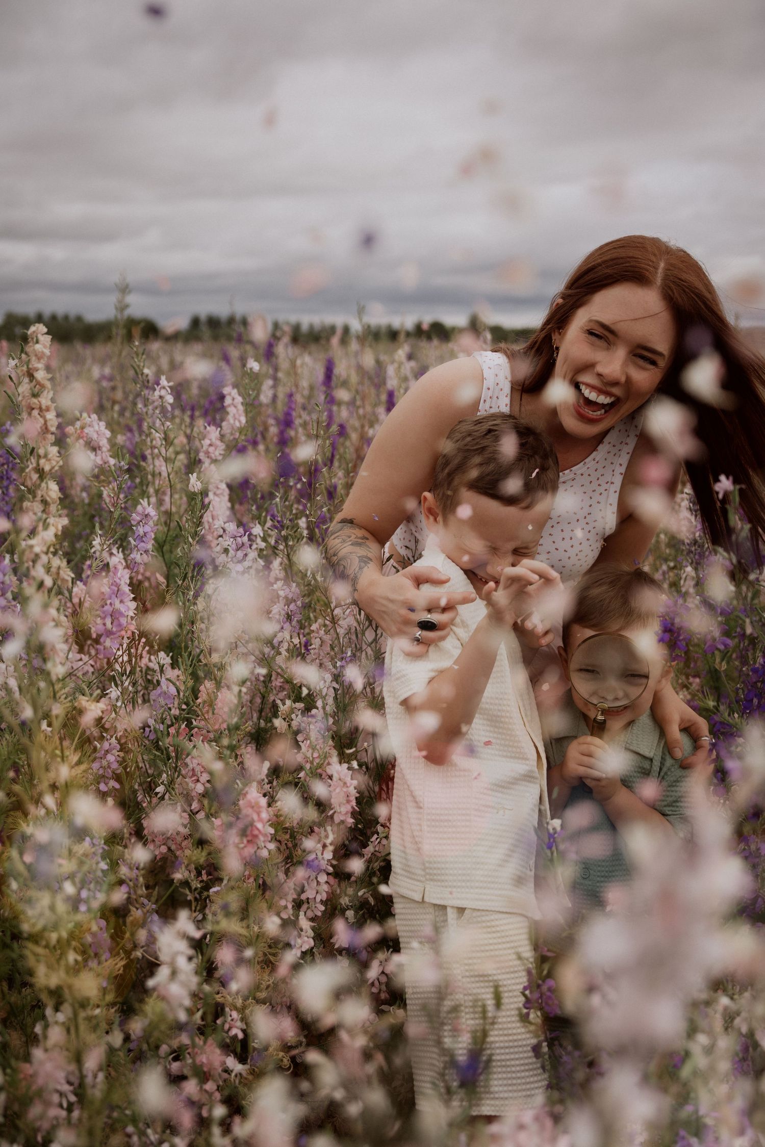 Mother laughing with her children in a wildflower field during a joyful storytelling mini photoshoot.