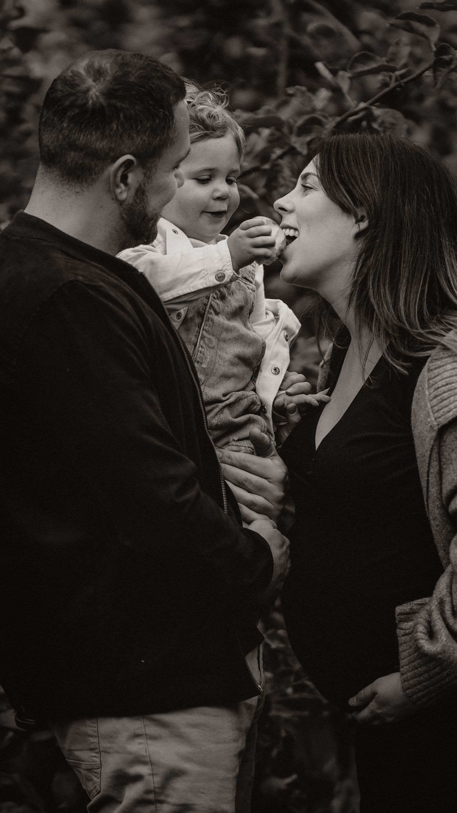 Family shares a tender moment in an apple orchard, celebrating pregnancy and togetherness in Elford