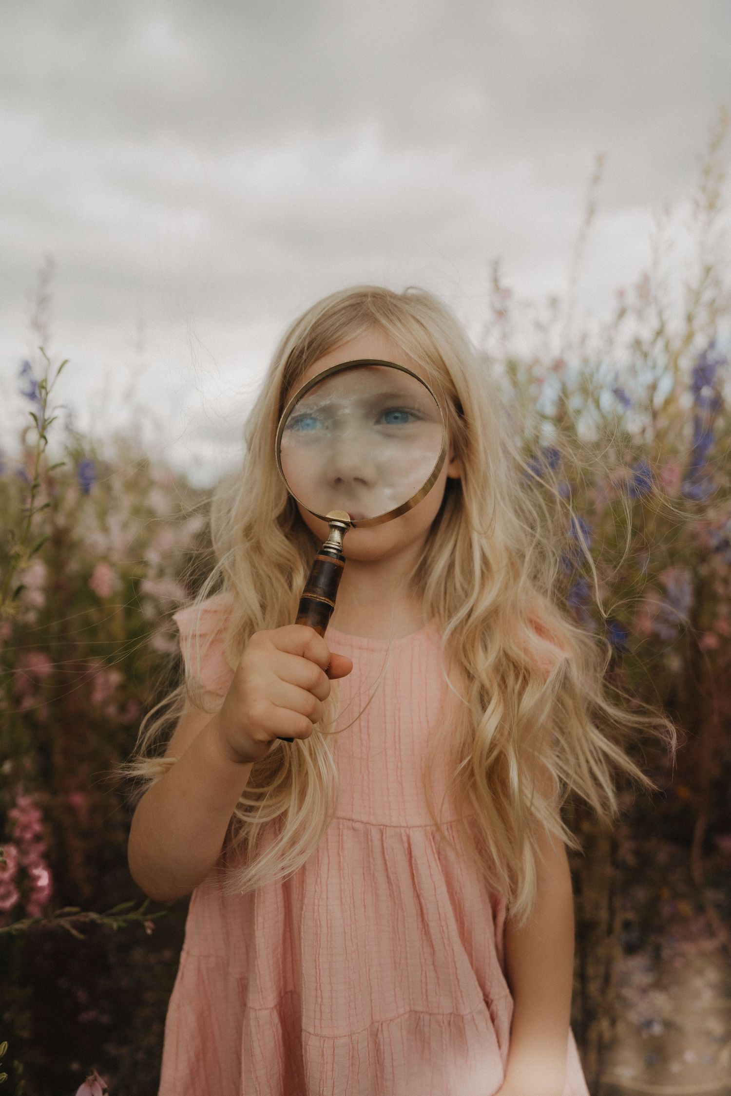 a girl looking through magnifying glass during Confetti Field Photoshoots