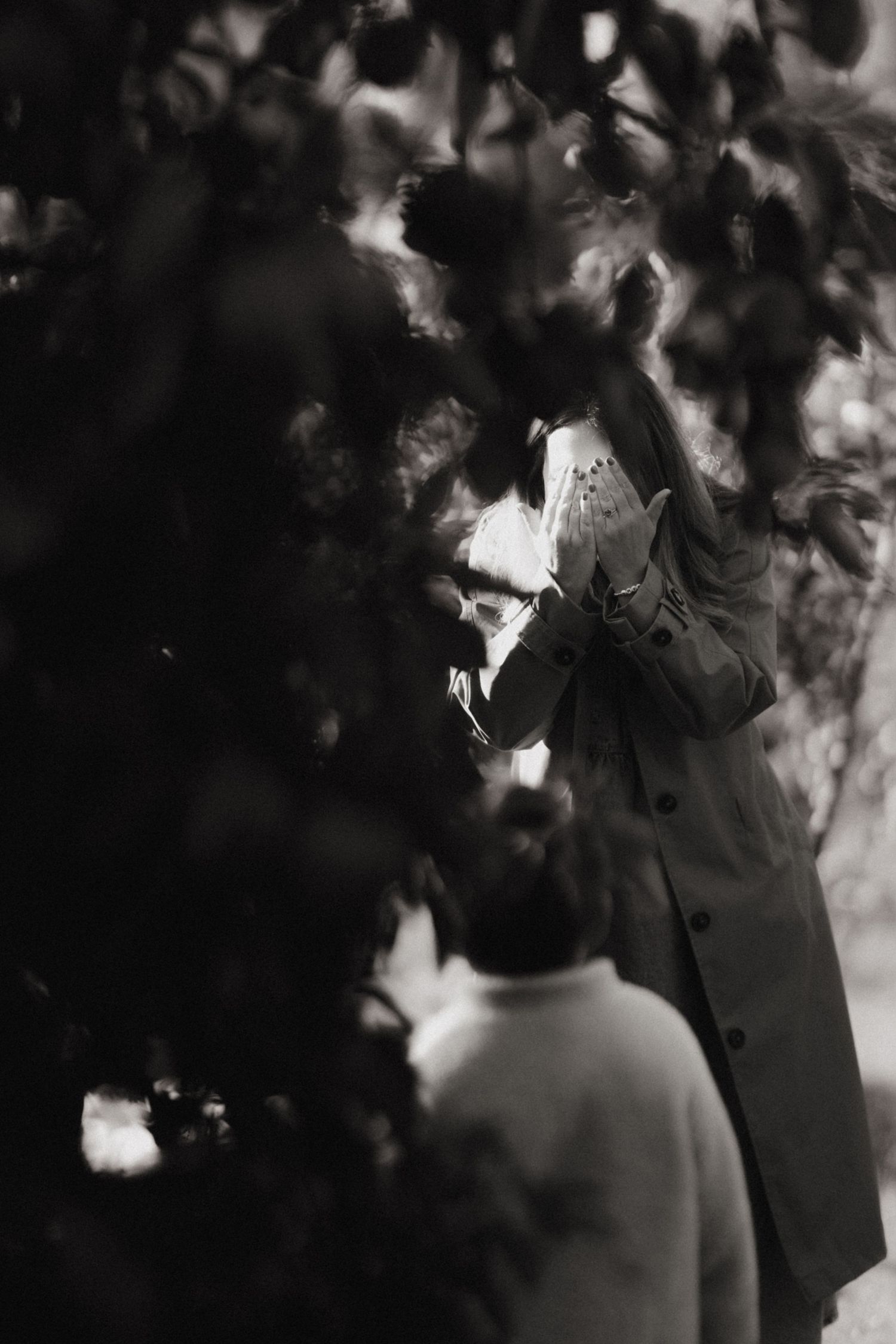 Couple shares a quiet moment under apple trees in timeless black and white.