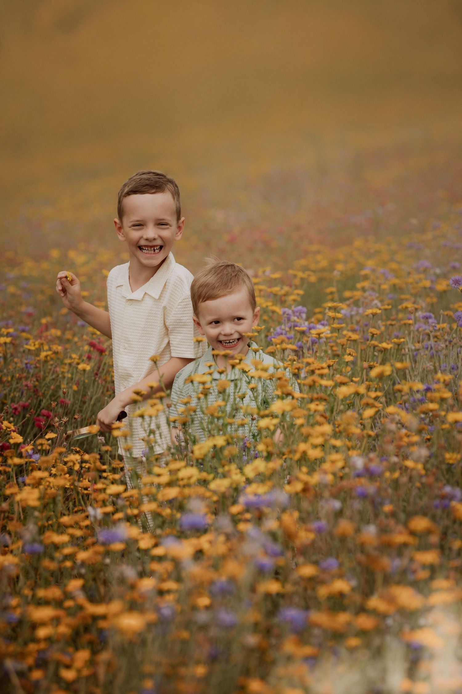 Two young siblings standing among colourful wildflowers during a relaxed outdoor documentary photoshoot.