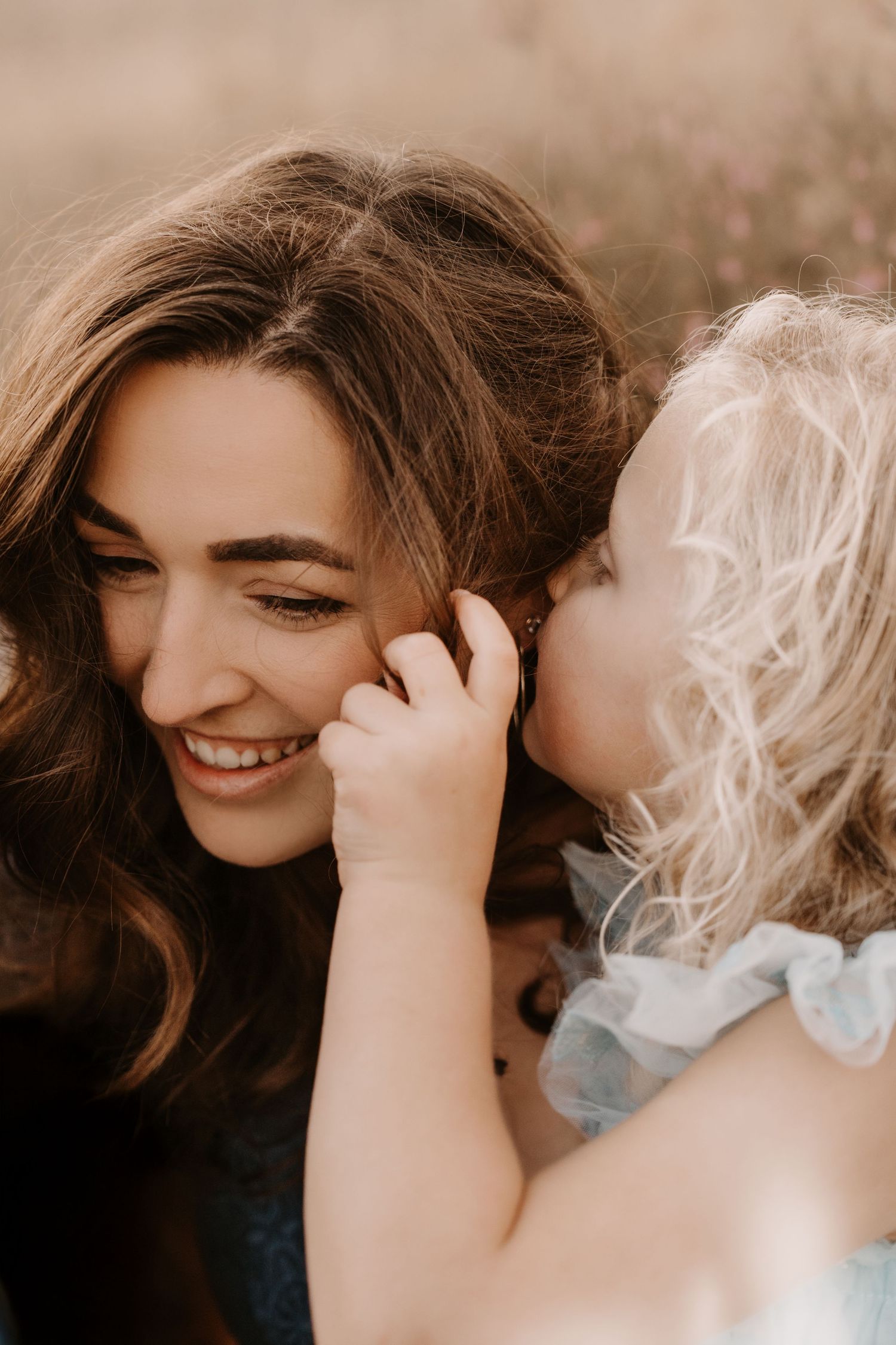 A parent smiling while a young child gently touches their face during an affectionate moment. Family Photoshoot in Moira